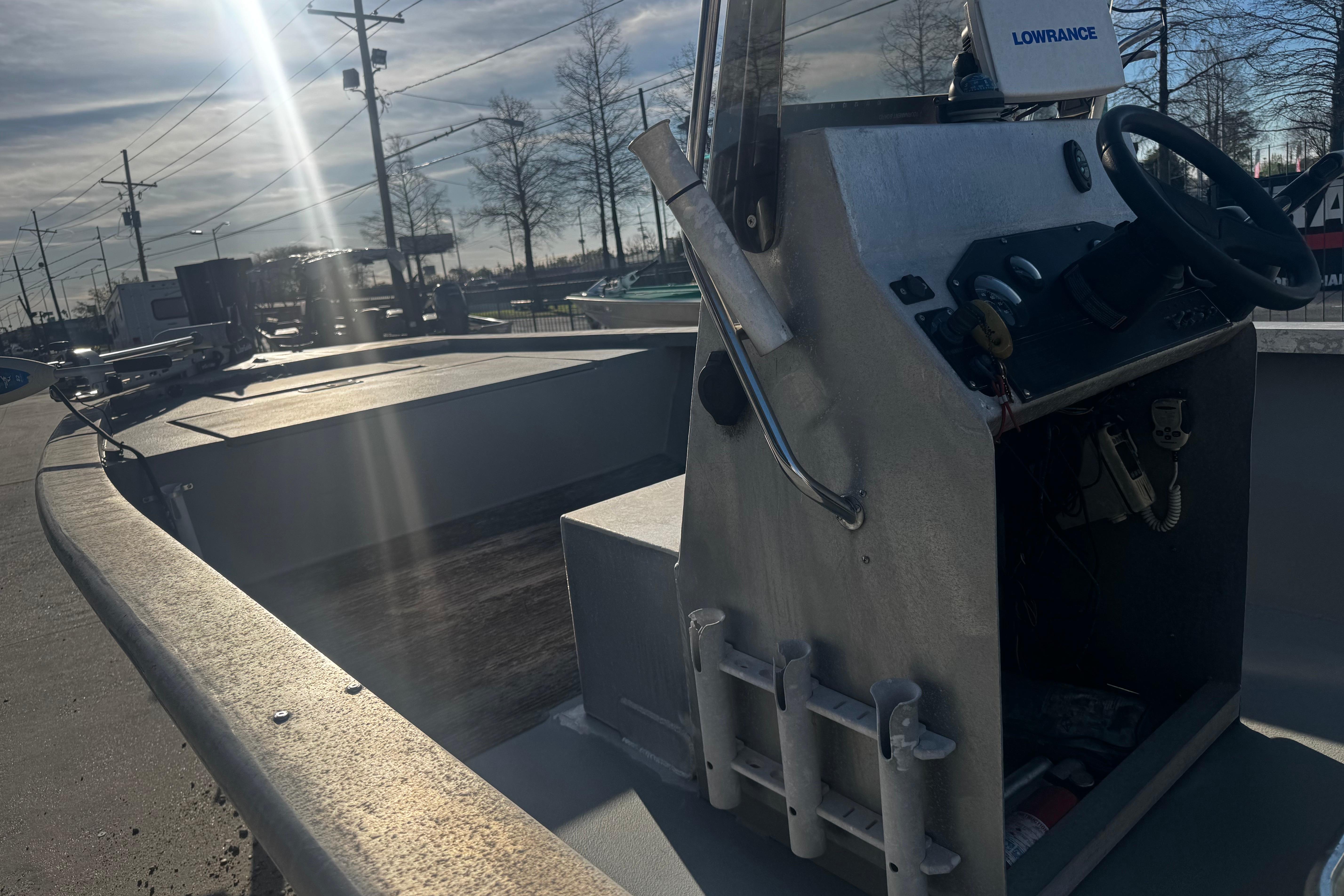 Aluminum boat with steering console, Lowrance equipment, and rod holders, under a sunny sky.