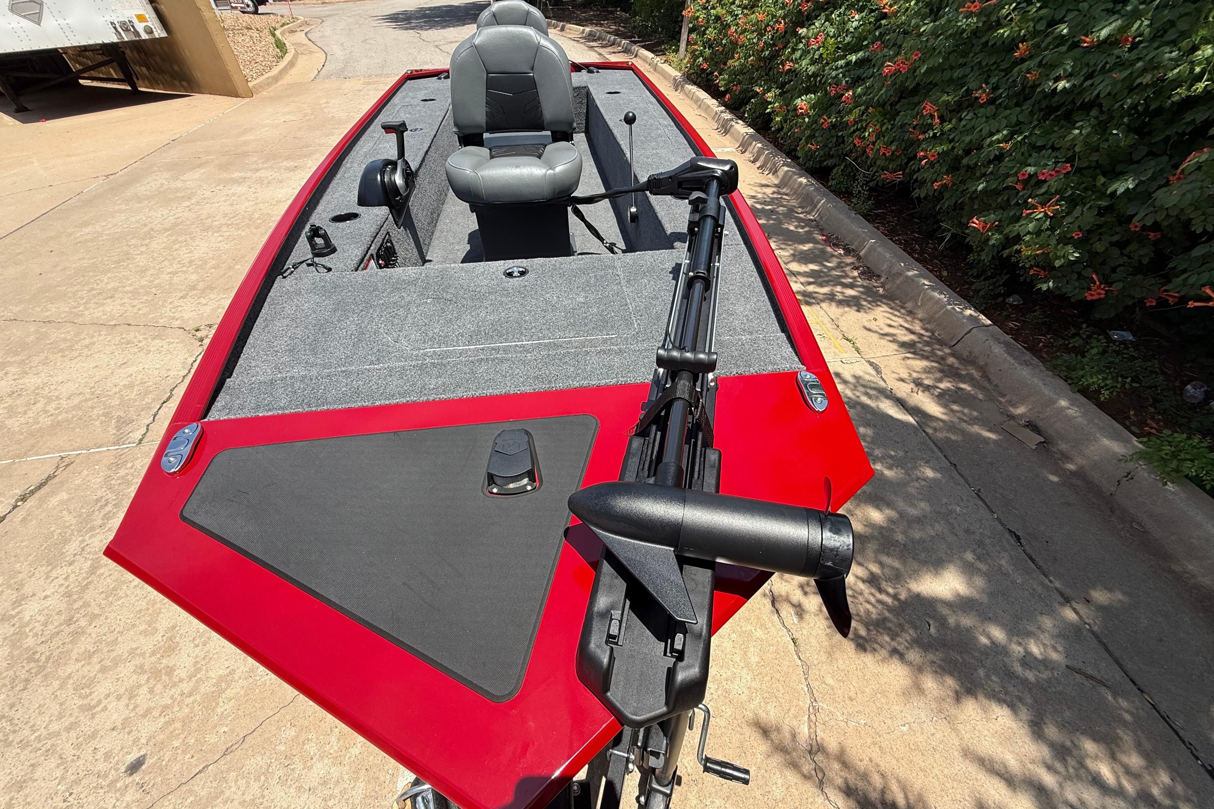 2025 Tracker Panfish 17 boat with red exterior and gray seating, parked on pavement.