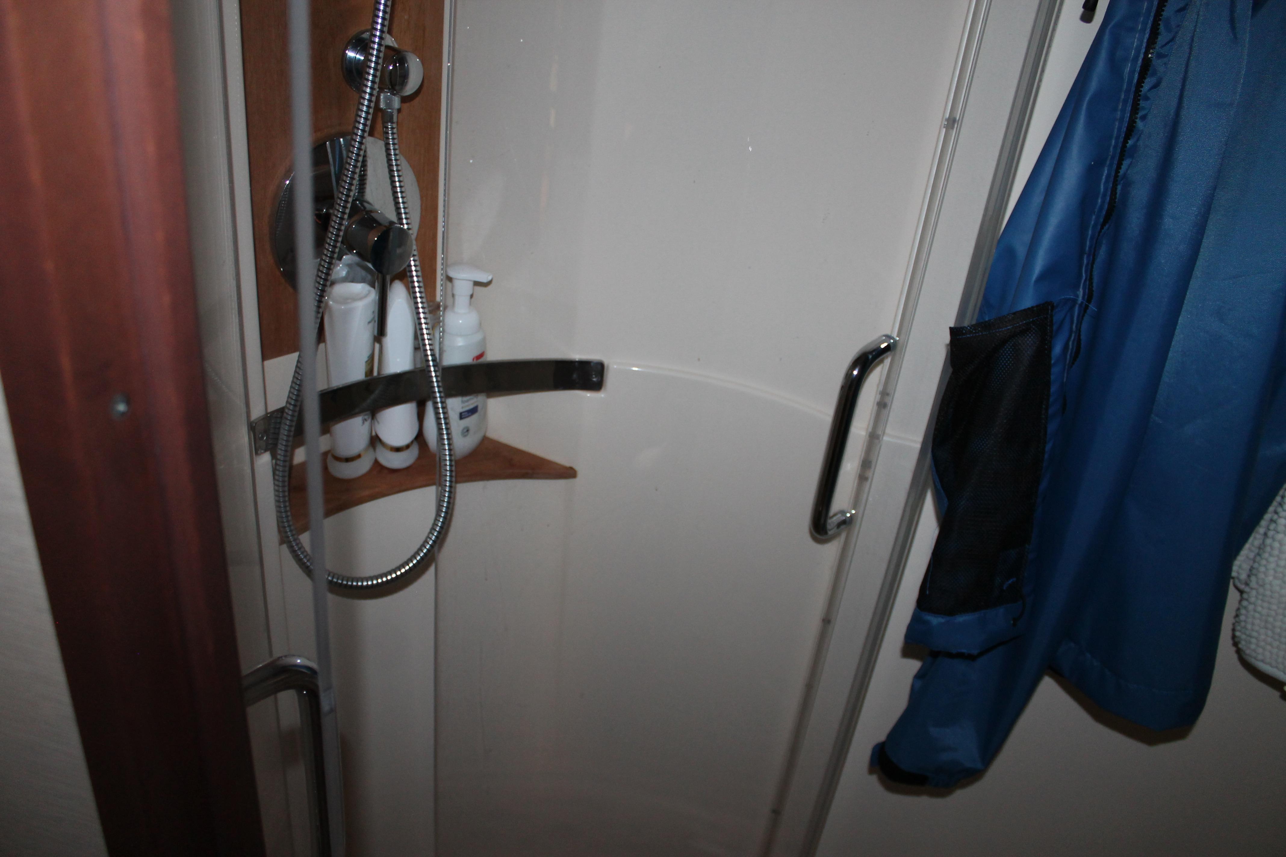 Shower area in 2015 Sea Ray 470 Sundancer yacht with toiletries and blue jacket.