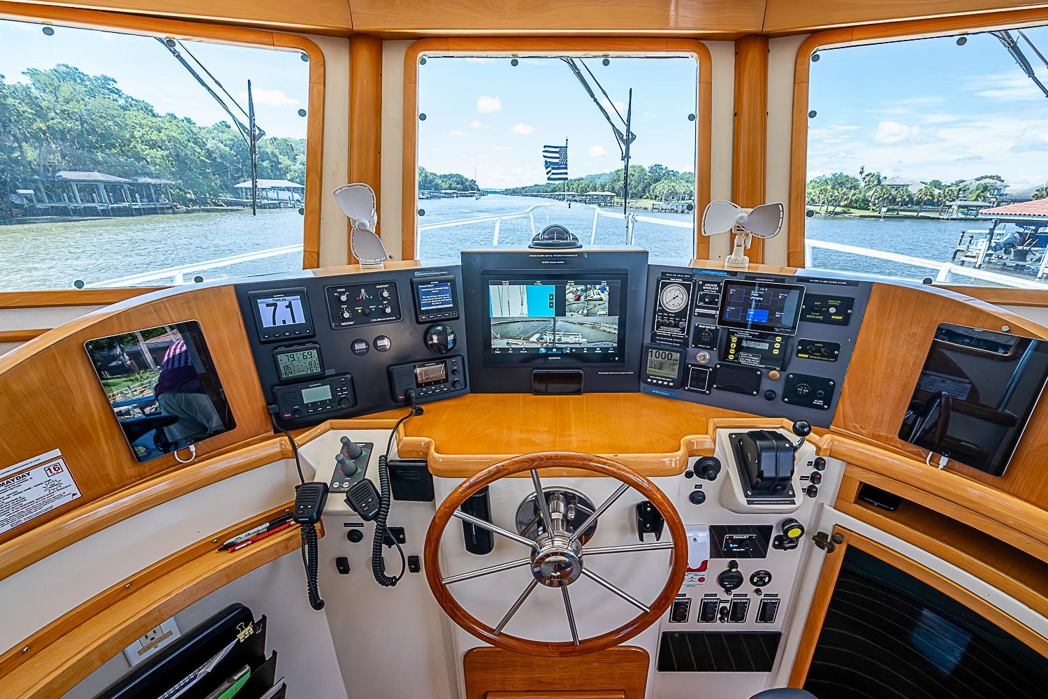 Helm of 2003 Magna Marine Nova Scotia 47 with navigation instruments and scenic river view.