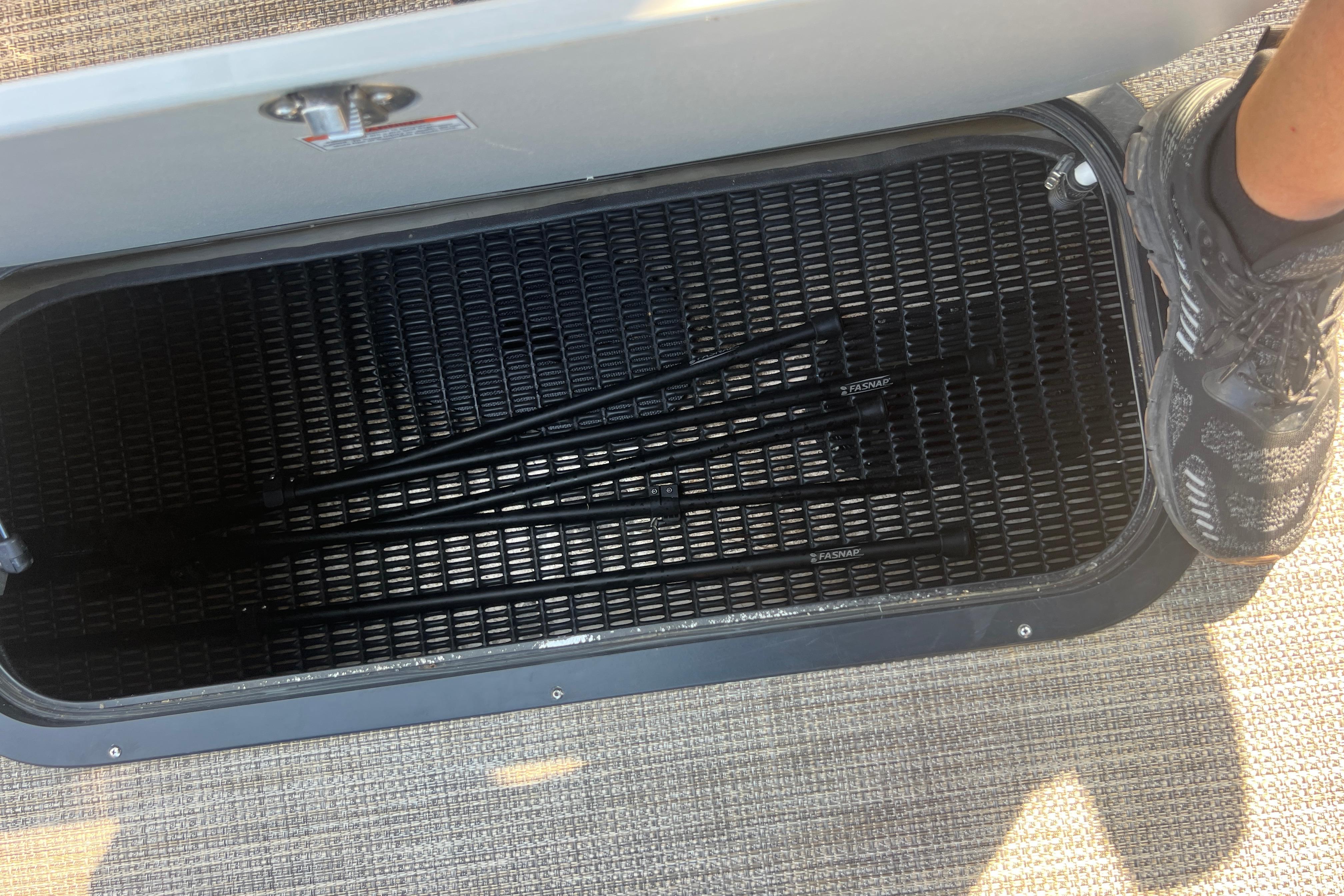Open storage compartment in 2022 Viaggio Lago V-U 22 boat, showing black rods inside.