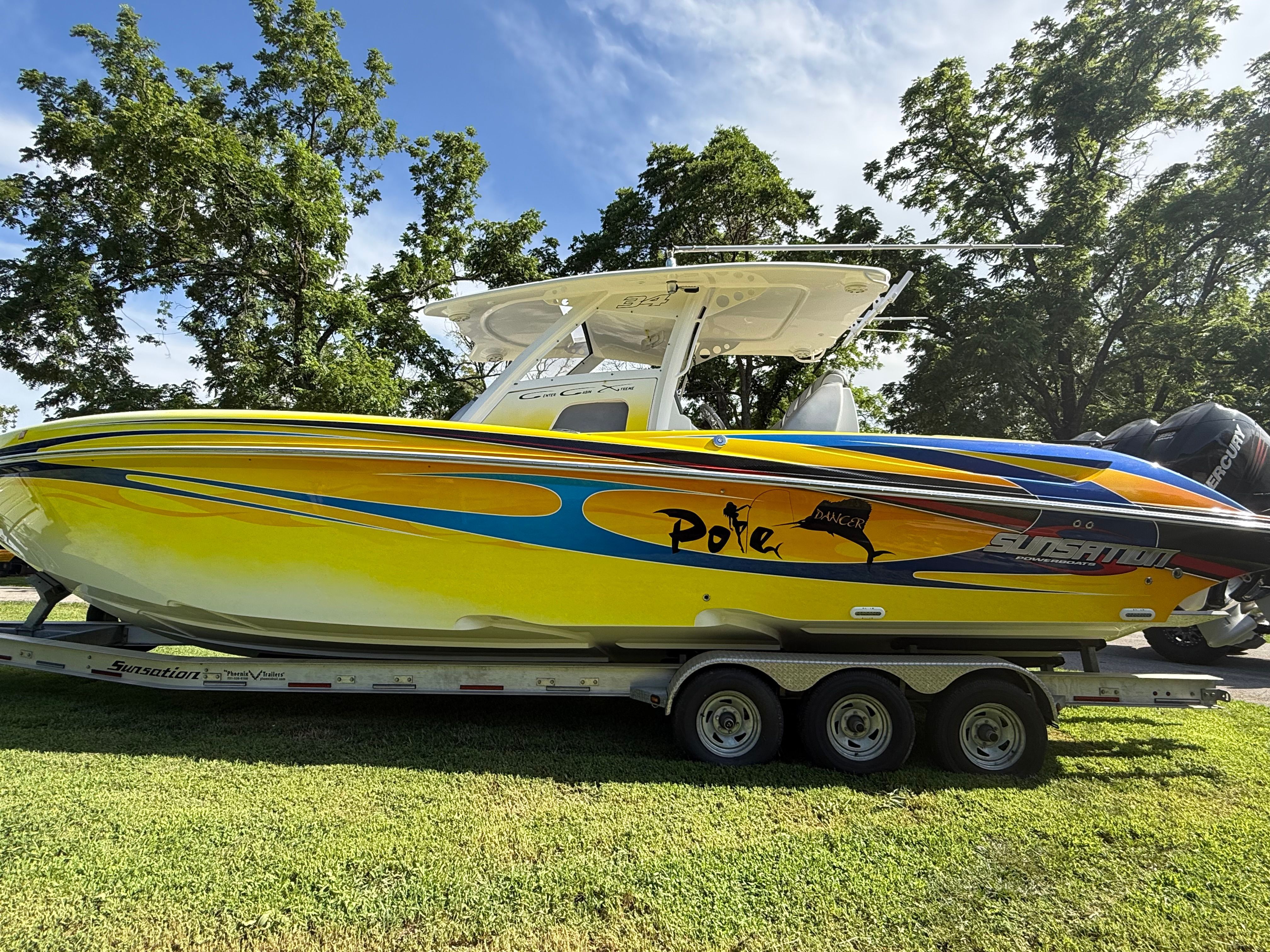A yellow 2014 Sunsation 34 CCX on a trailer, surrounded by trees.