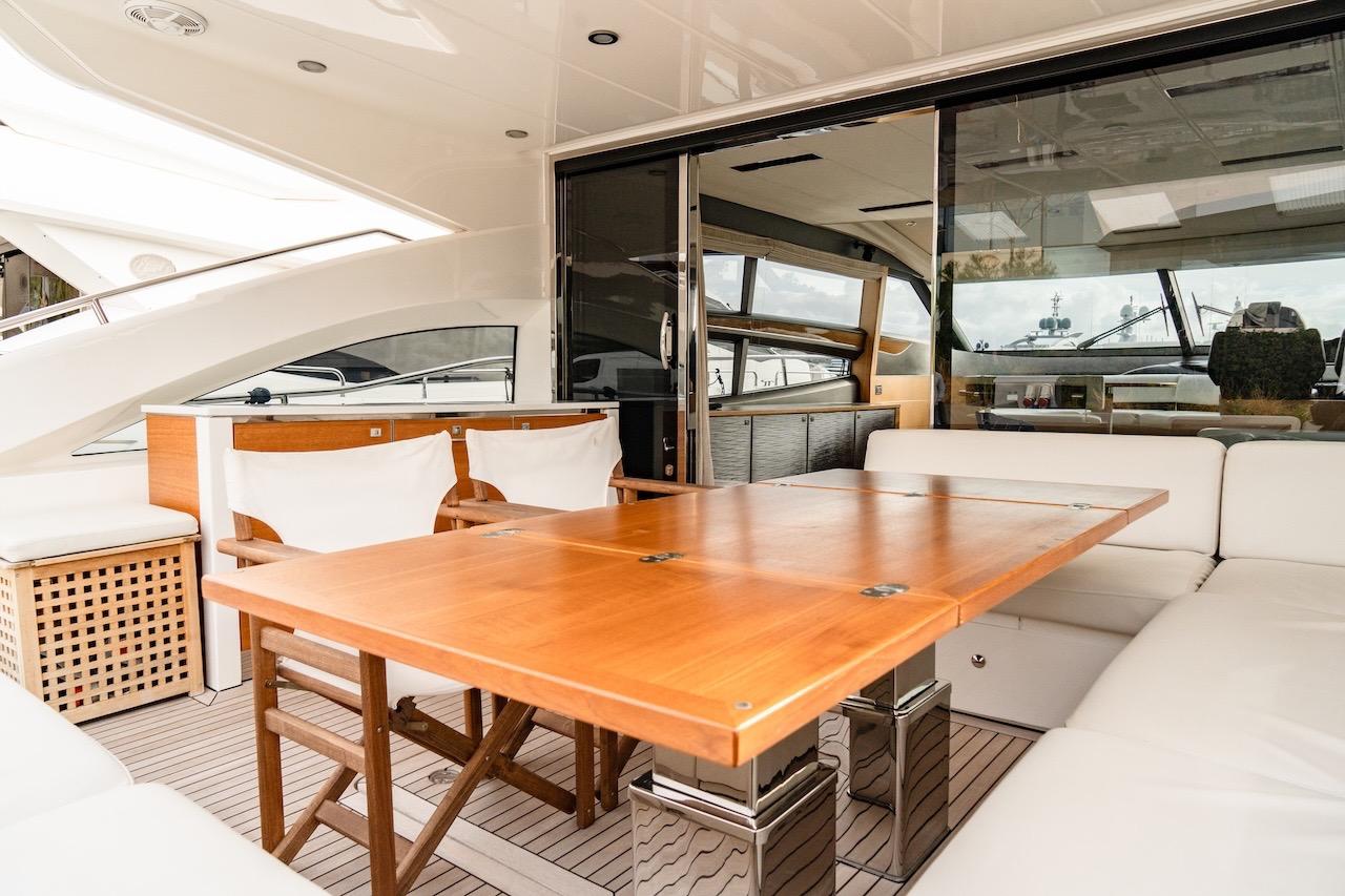 Luxurious 2012 Princess V72 yacht interior with elegant wooden dining table and white seating.
