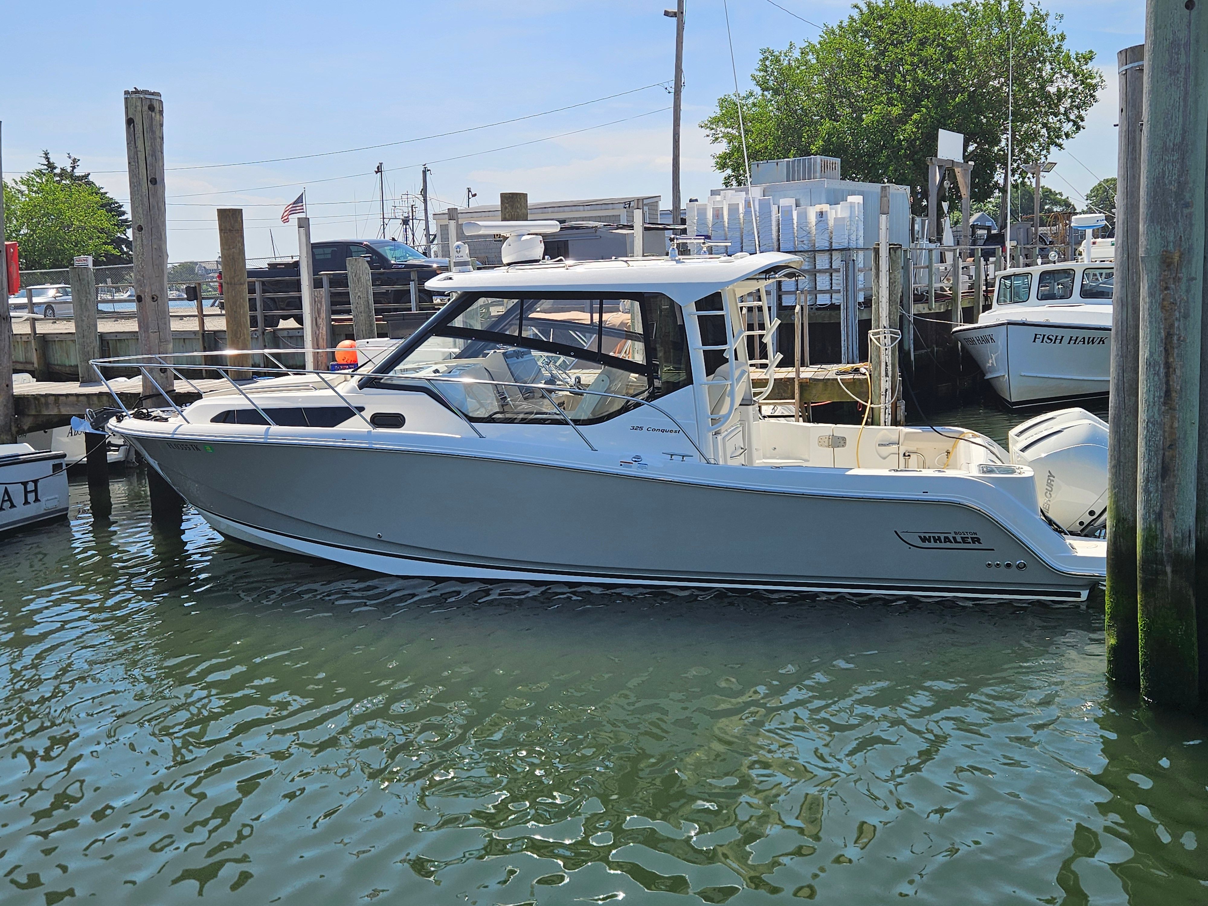 A 2023 Boston Whaler 325 Conquest is docked in the water.