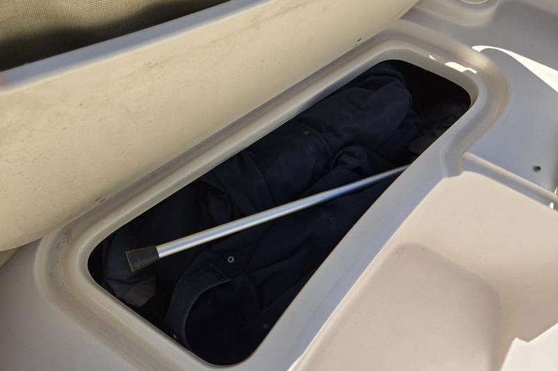 Storage compartment in a 2007 Grady-White Tournament 205 boat, containing a metal rod.