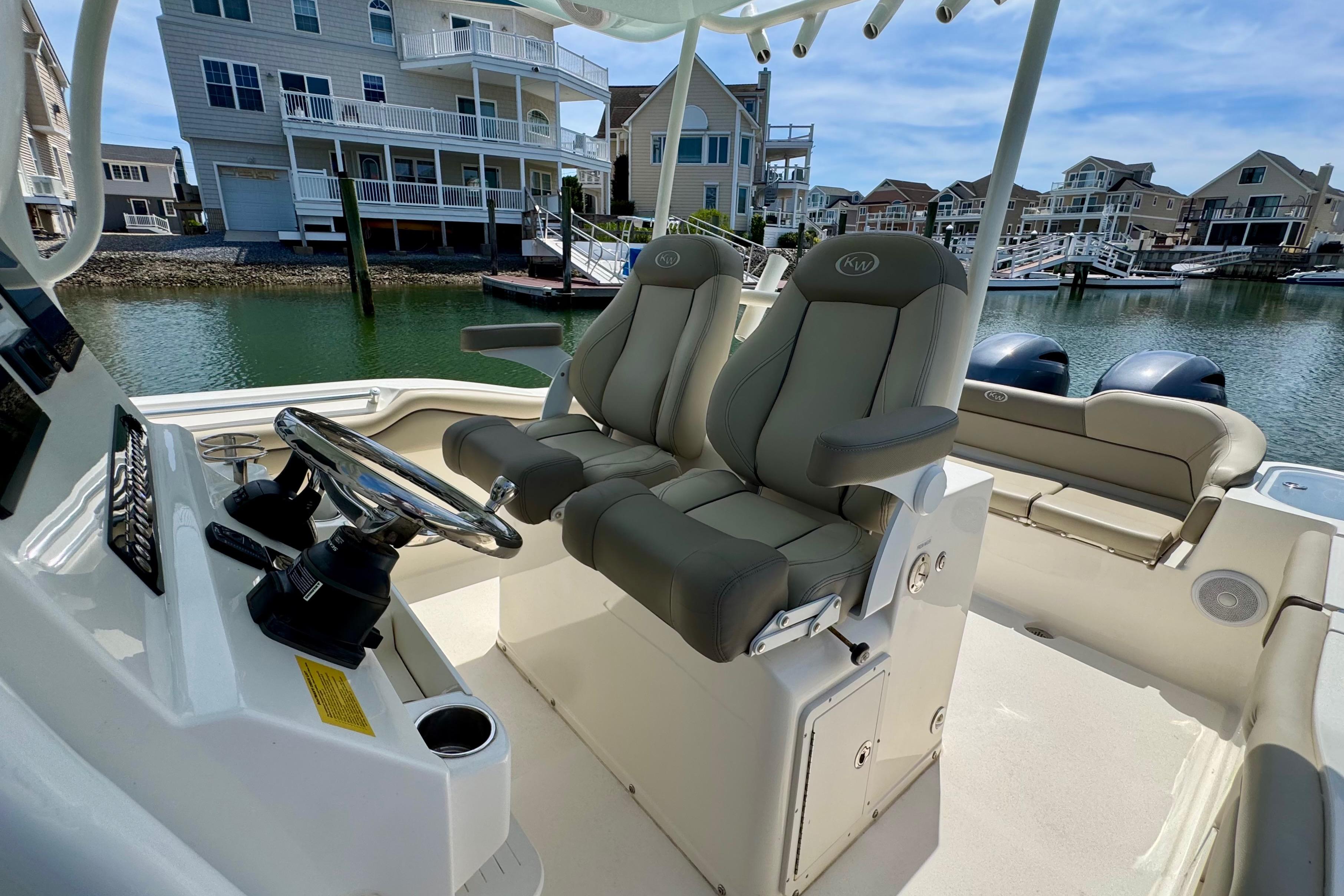 2022 Key West 263 FS boat interior with dual seats and steering wheel in a marina setting.