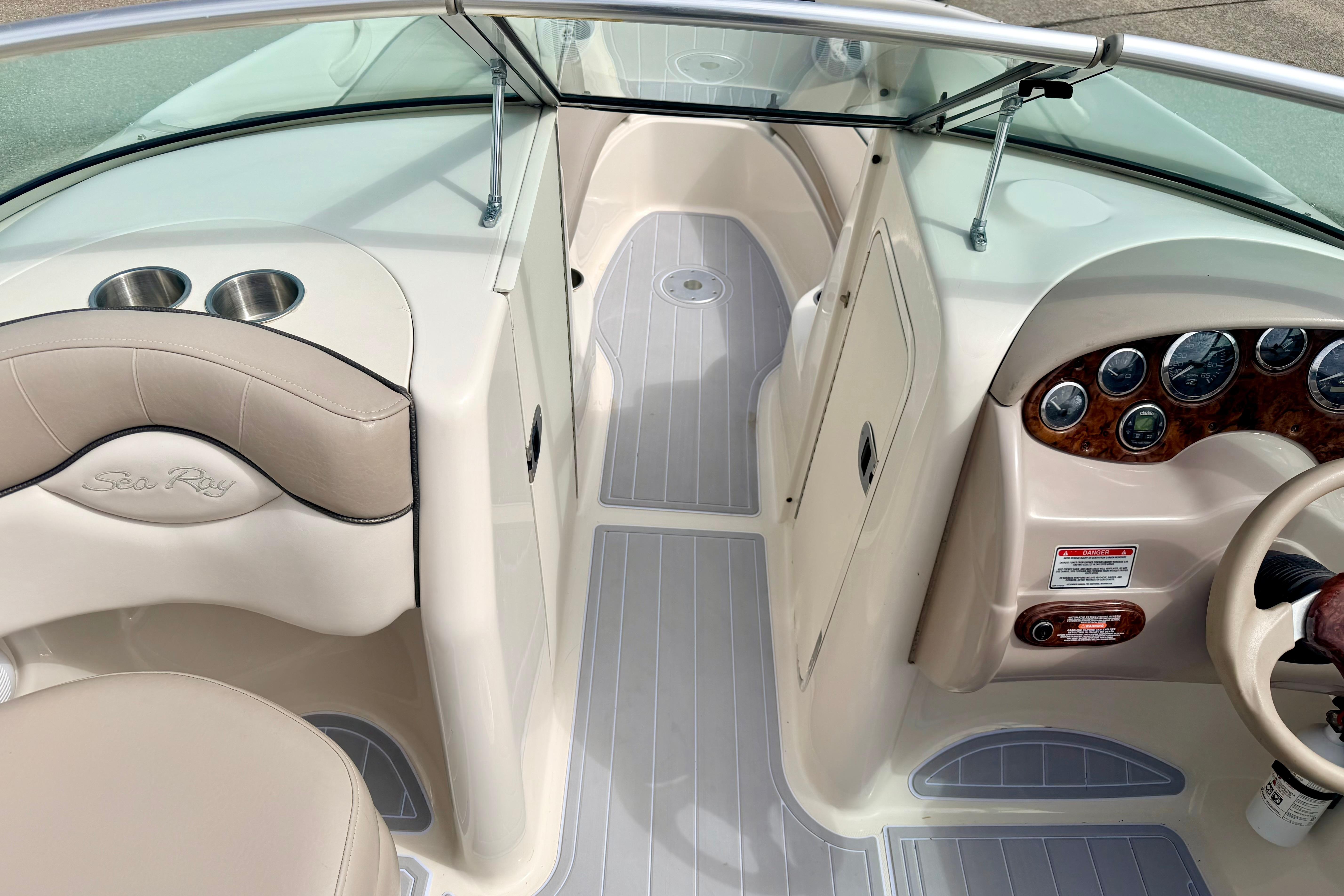 2003 Sea Ray 200 Sundeck interior with beige seating and dashboard controls.