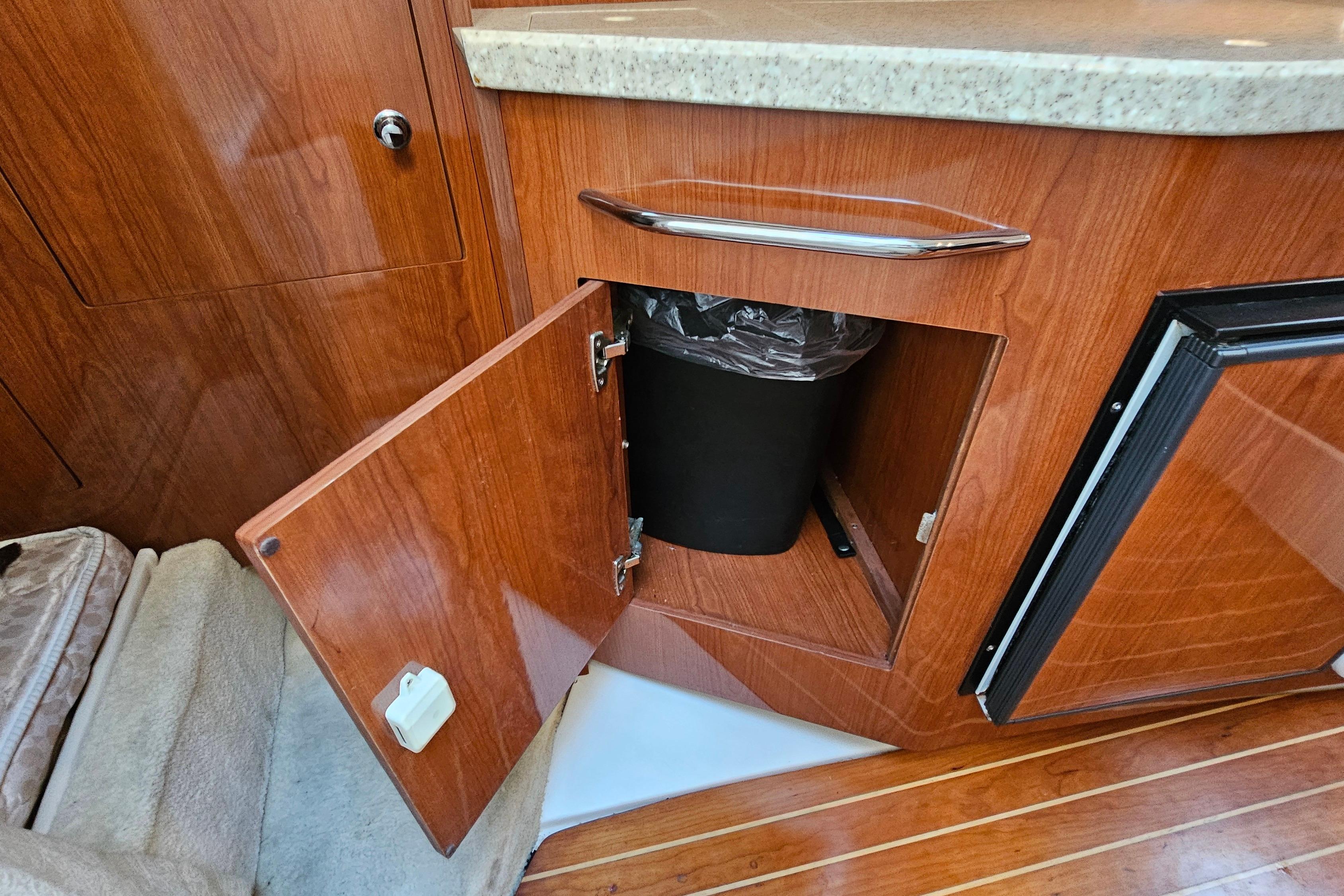 2005 Regal 3060 Window Express interior with open wooden cabinet and trash bin.
