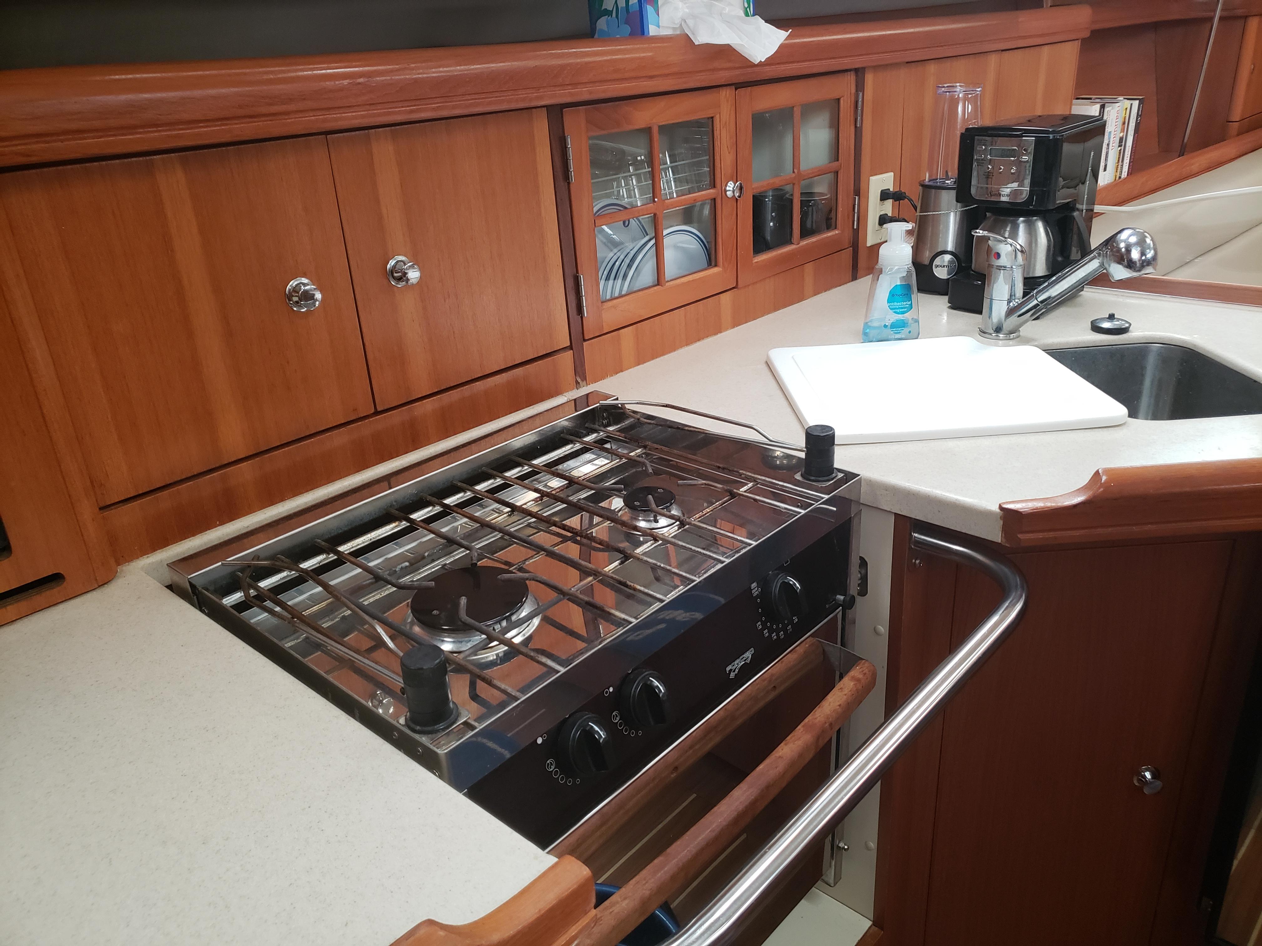 2006 Hunter 41 yacht kitchen with stove, sink, and wooden cabinetry.