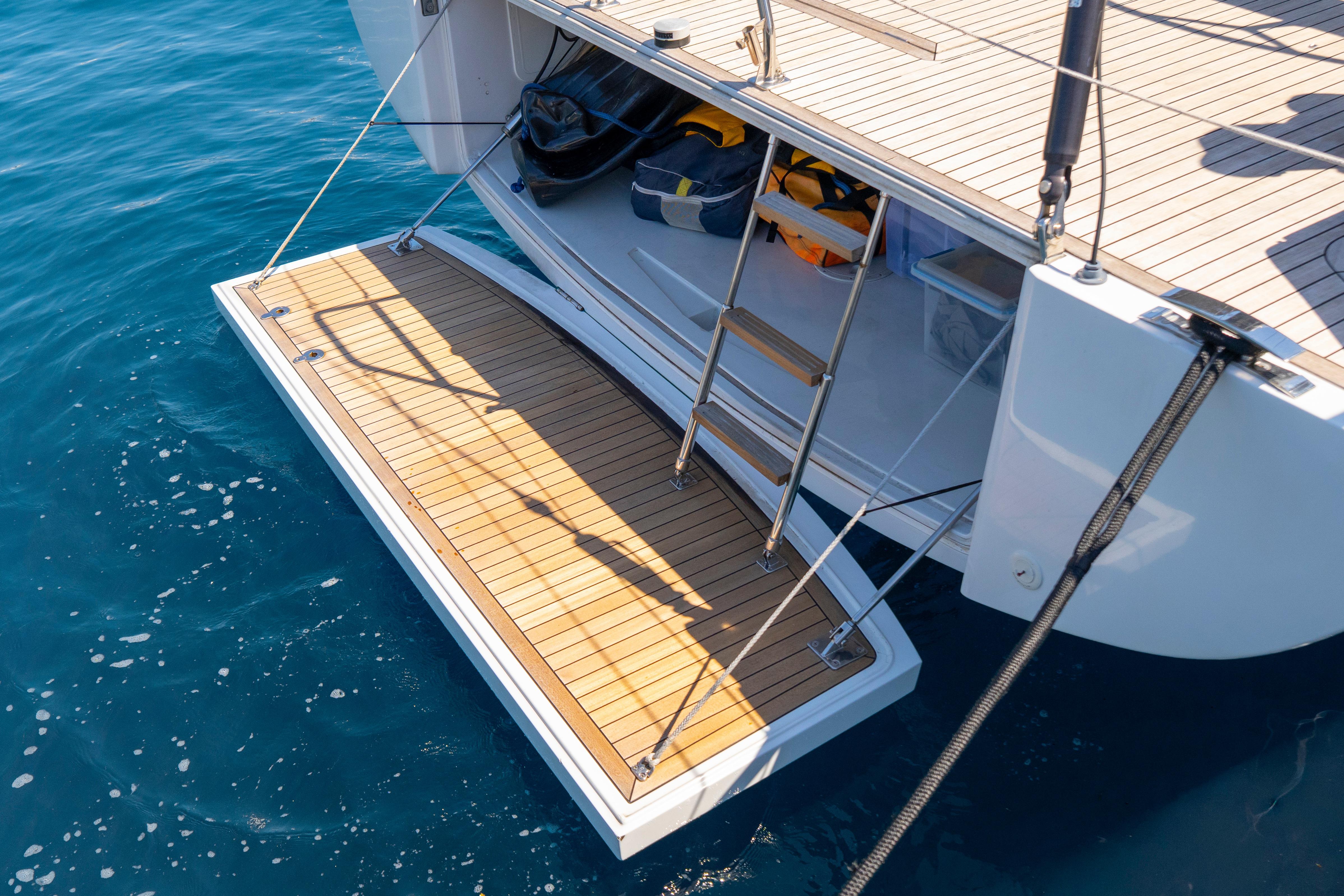 Grand Soleil 58 yacht's teak swim platform and ladder, 2016 model, on clear blue water.