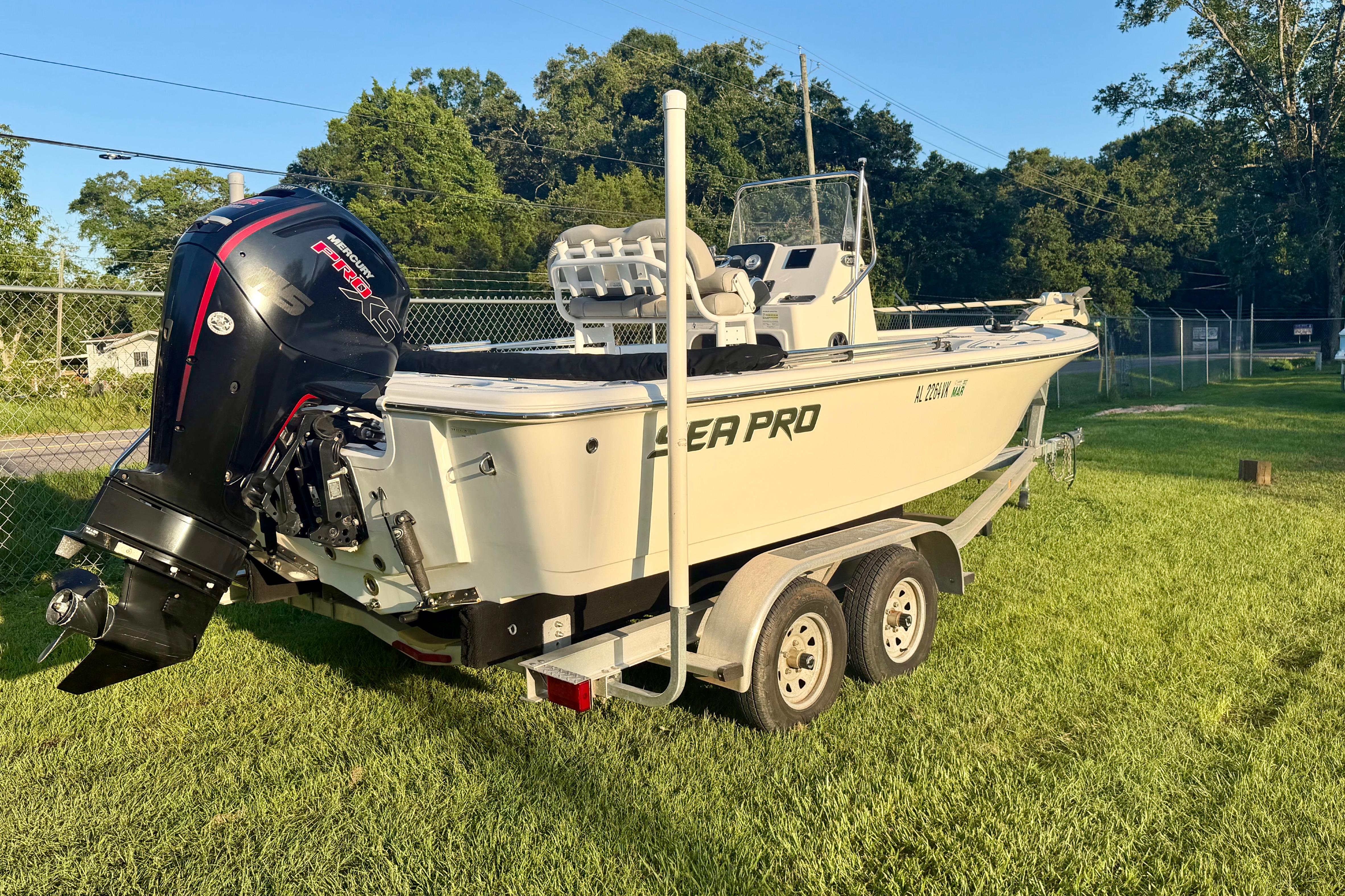 2018 Sea Pro 208 Bay boat on trailer with Mercury engine, parked on grass.