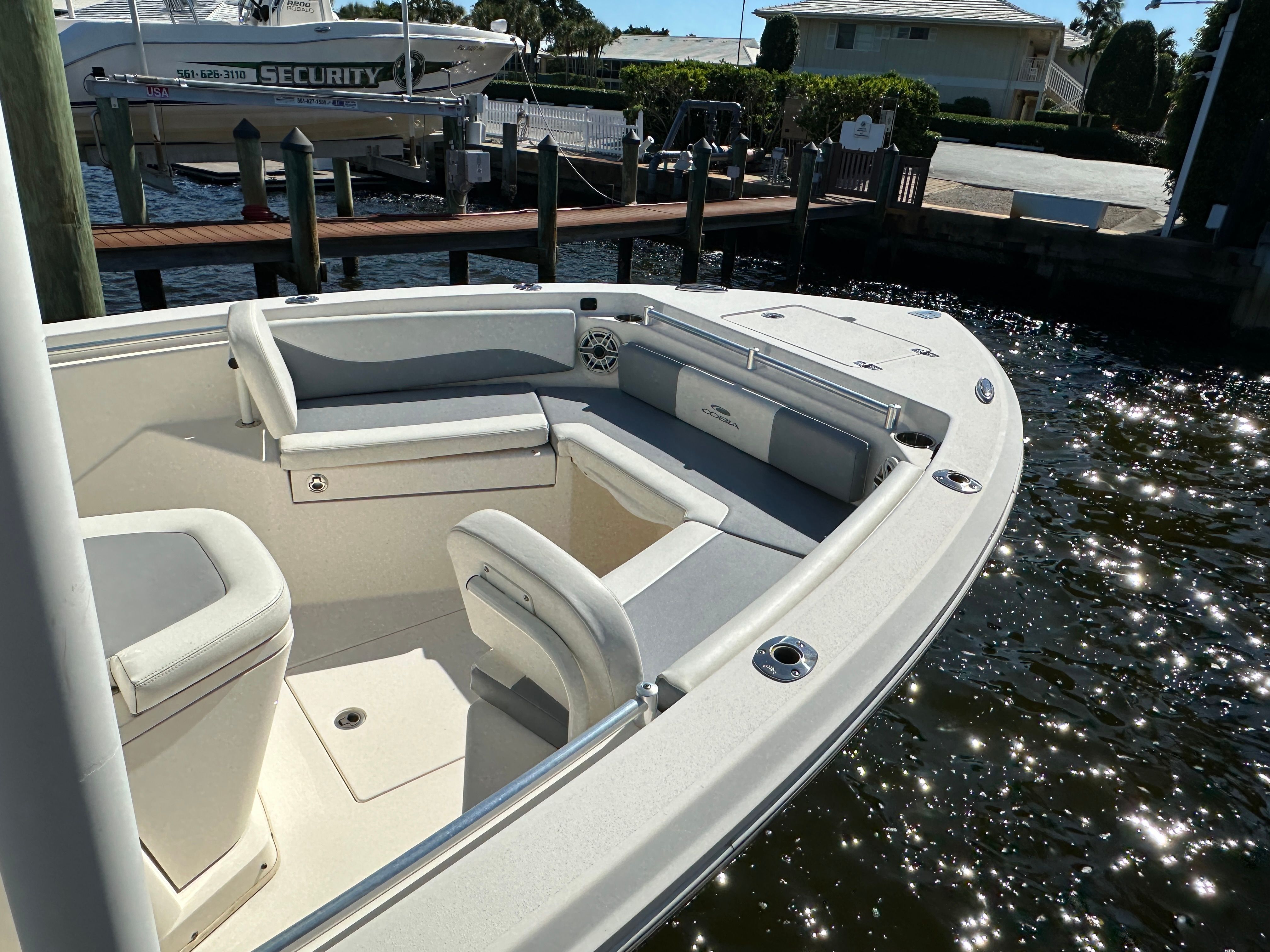 The image shows the bow of a 2022 Cobia 240 Center Console boat docked by the water.