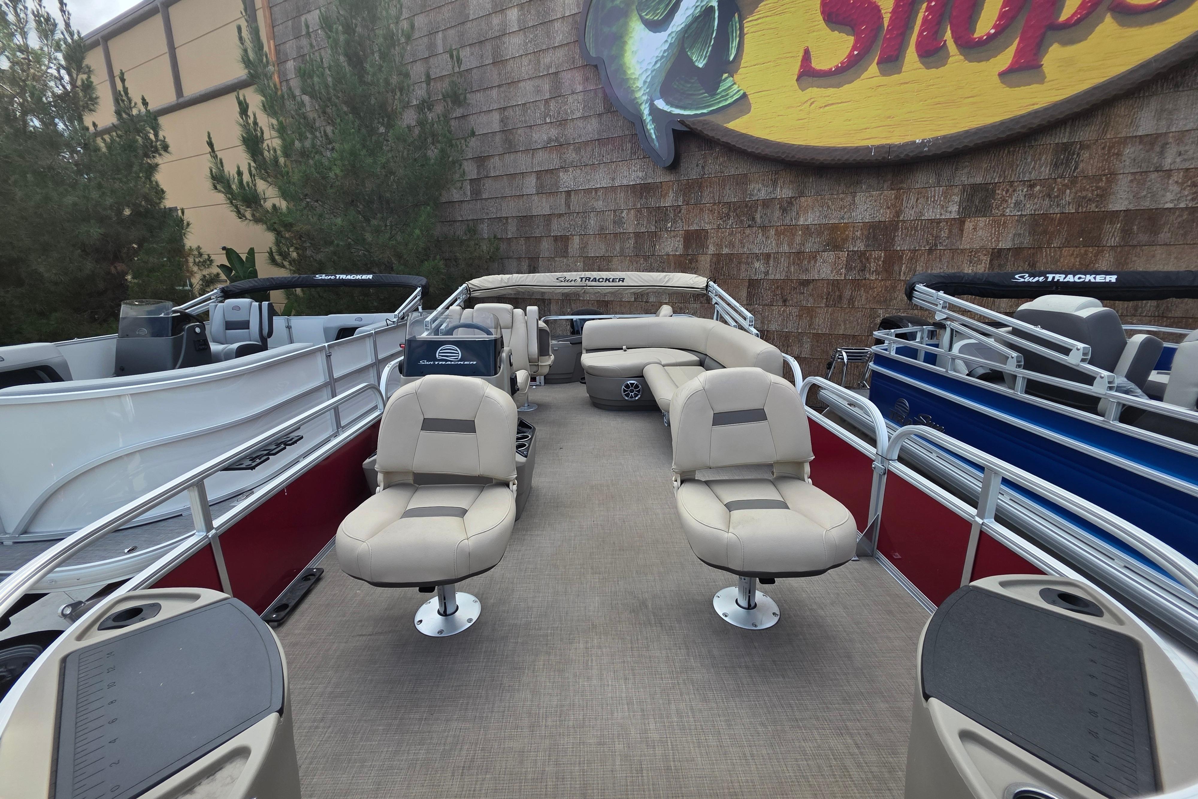 2025 Sun Tracker Bass Buggy 18 DLX pontoon boat with beige seating, displayed outdoors.