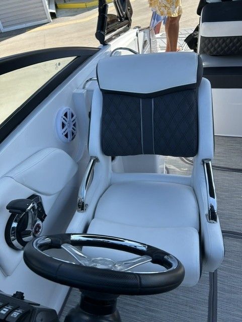 A luxurious white boat seat with black accents and a steering wheel.