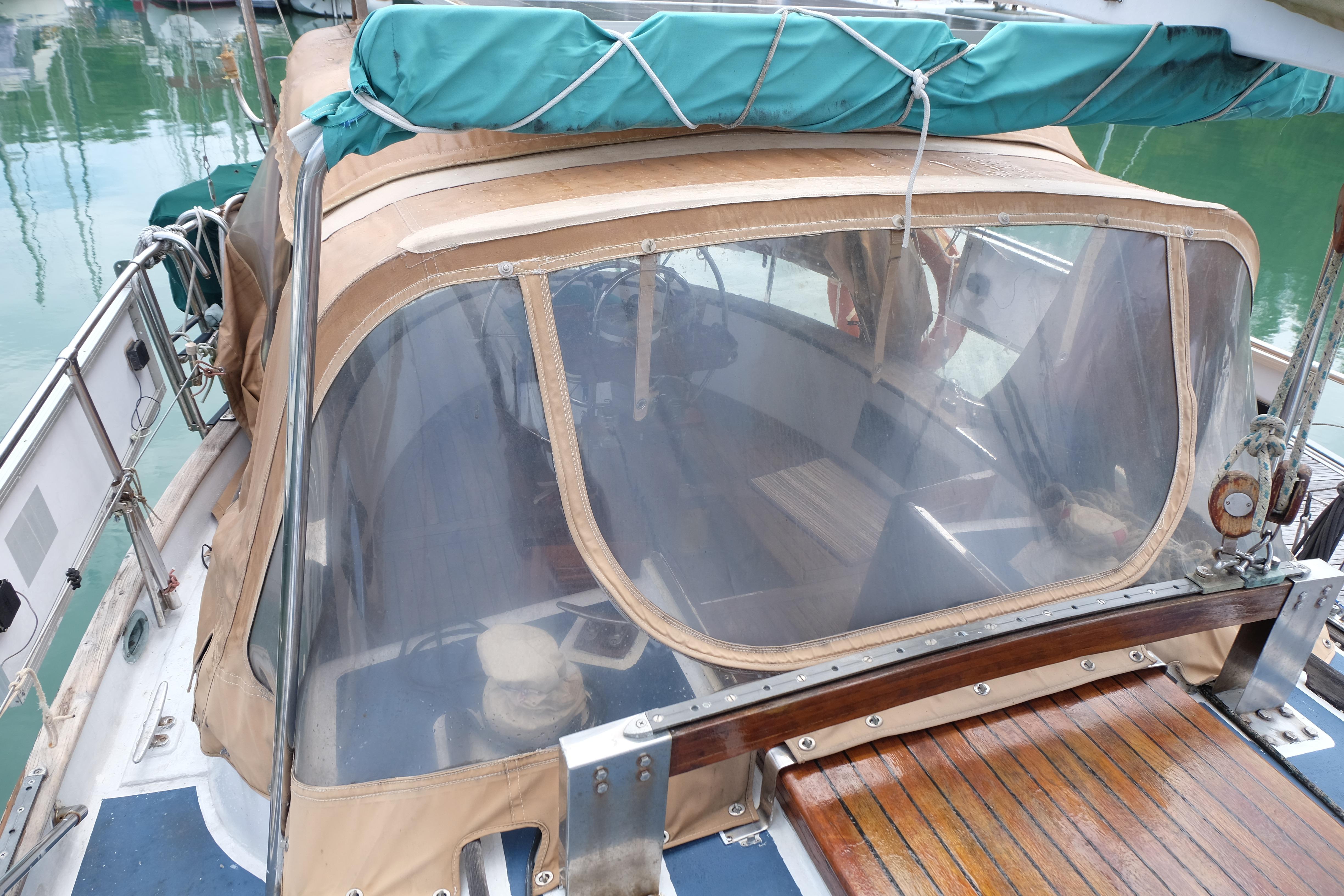 1979 Westwind 35 sailboat cockpit with tan canvas cover and clear windows in a marina.