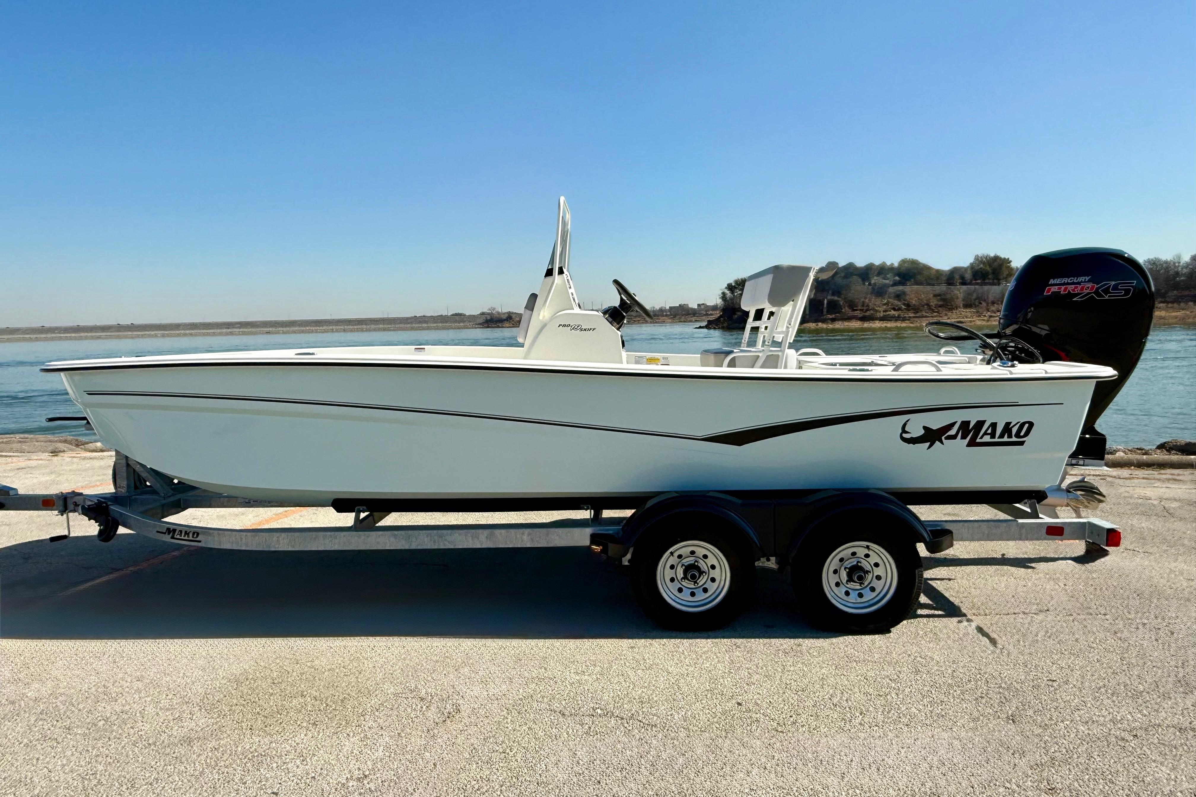 2024 Mako Pro Skiff 19 CC boat on trailer by waterfront.