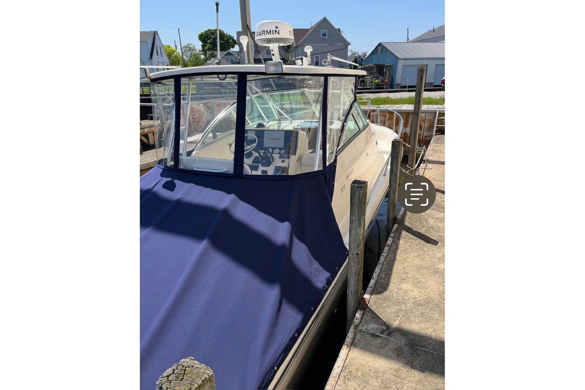 2000 Pursuit 3070 Offshore Center Console boat docked with blue cover.
