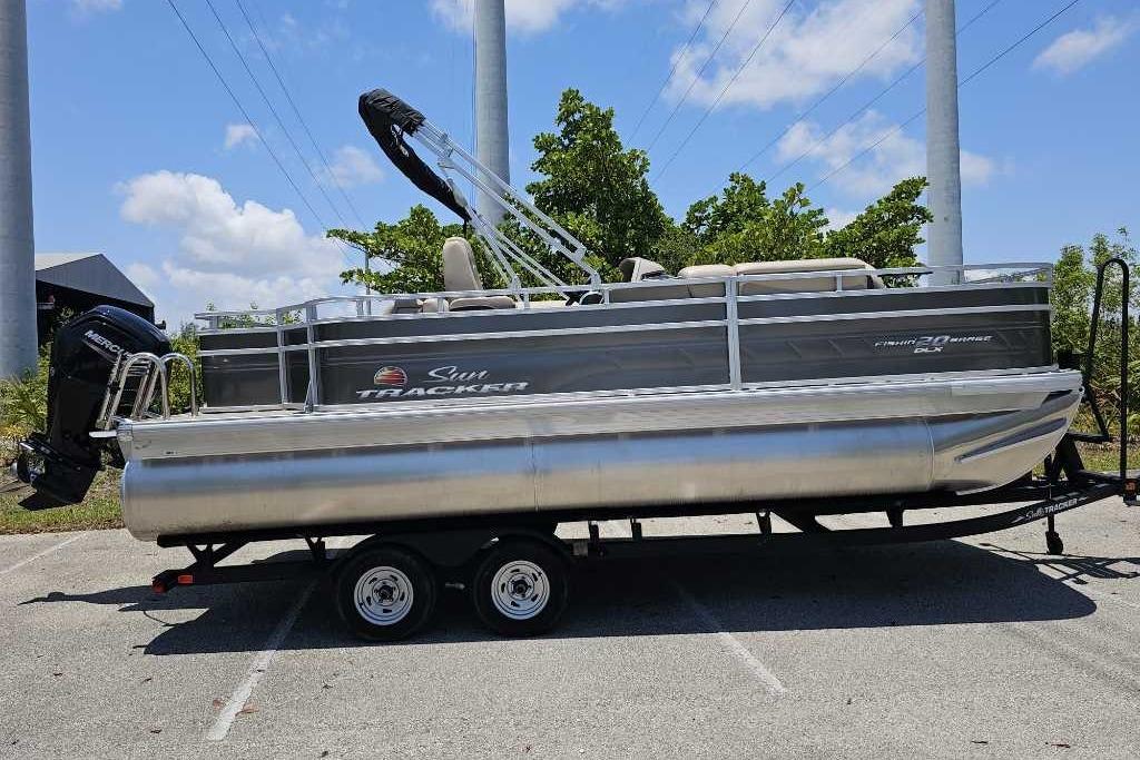 2025 Sun Tracker SportFish 20 DLX pontoon boat on trailer, parked outdoors.
