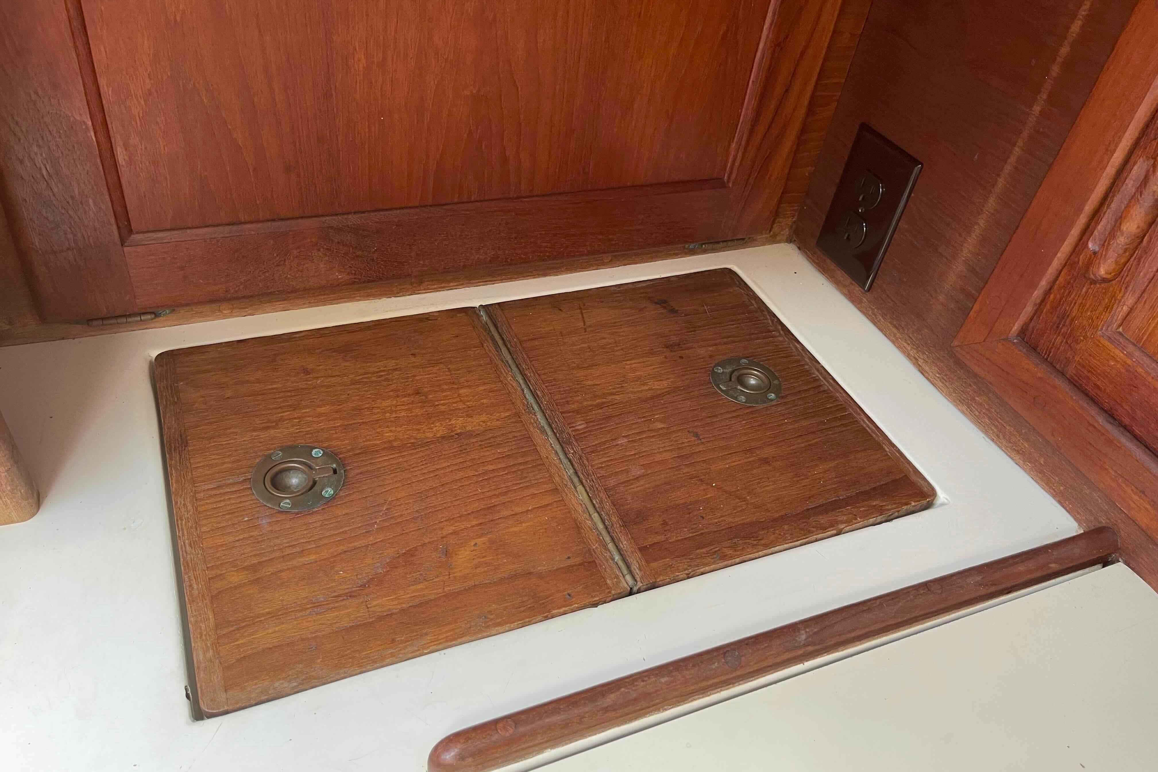 Wooden interior detail of a 1987 Pacific Seacraft 34 sailboat, featuring storage compartments.