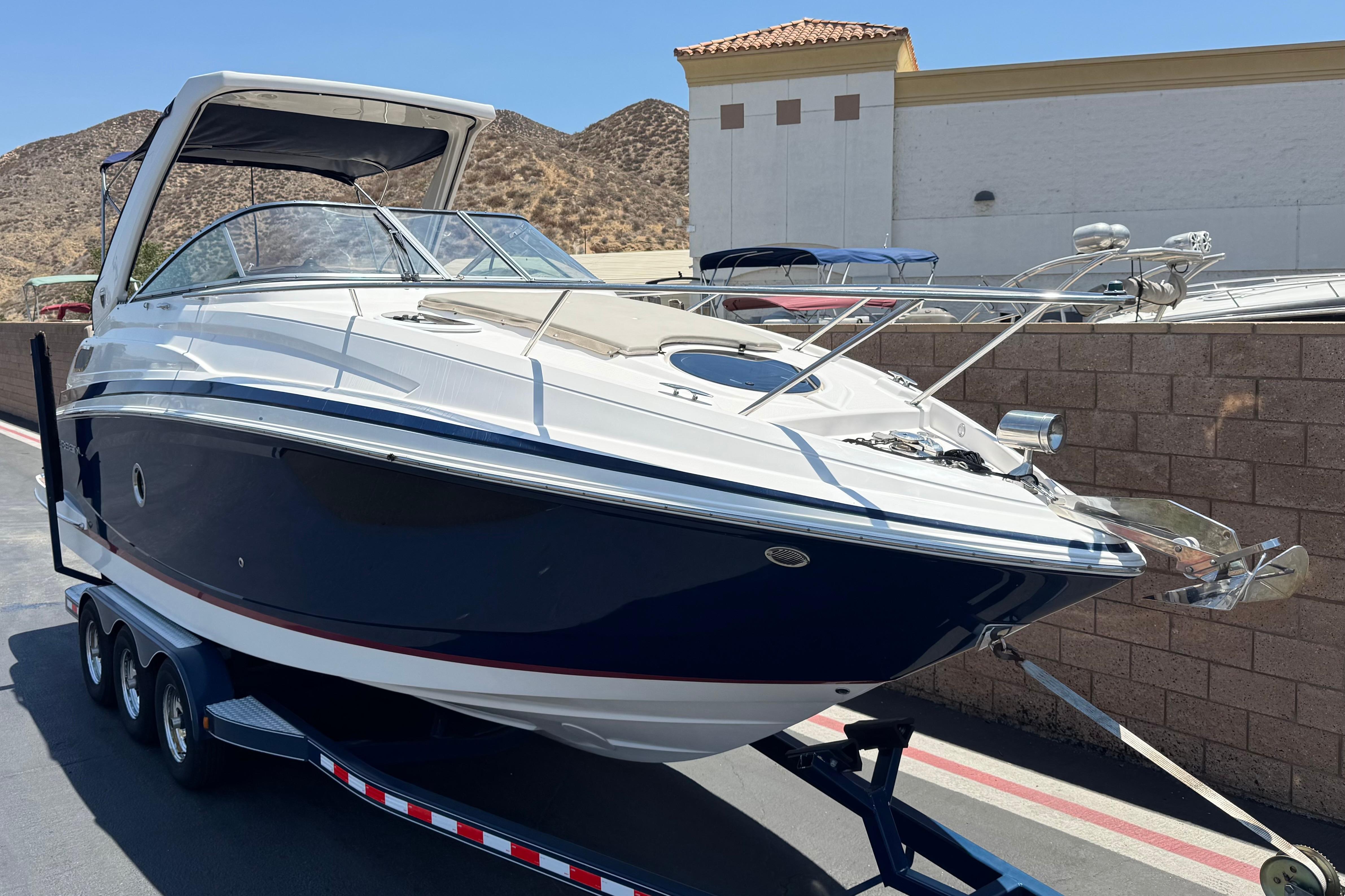 2013 Regal 28 Express boat on trailer, parked outdoors near a brick wall.