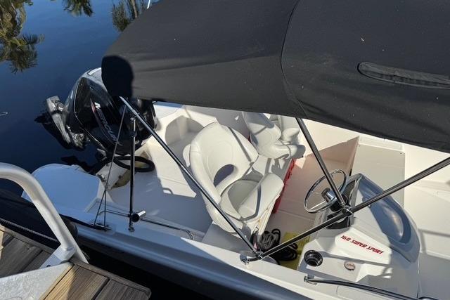 2024 Boston Whaler 160 SS boat with canopy, docked on calm water.