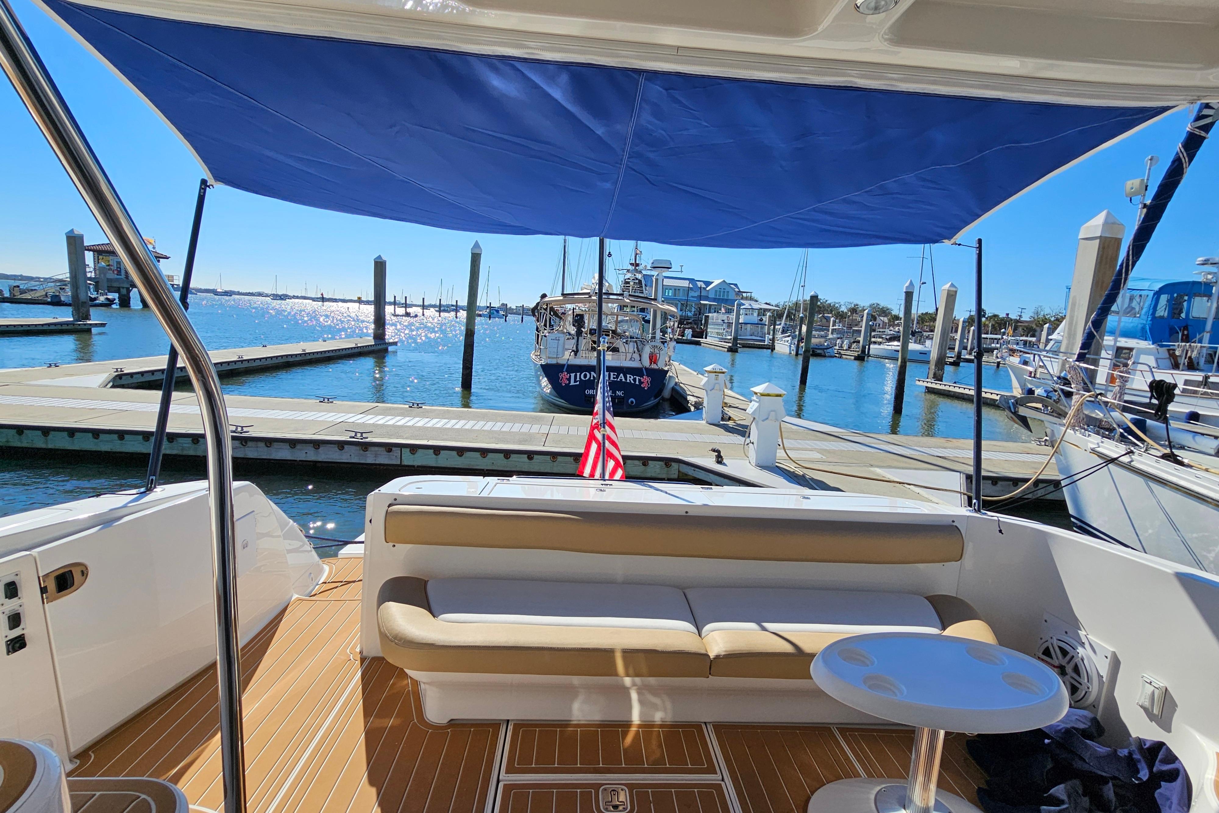 2006 Sea Ray 580 Sedan Bridge yacht docked at marina, featuring spacious seating and blue canopy.