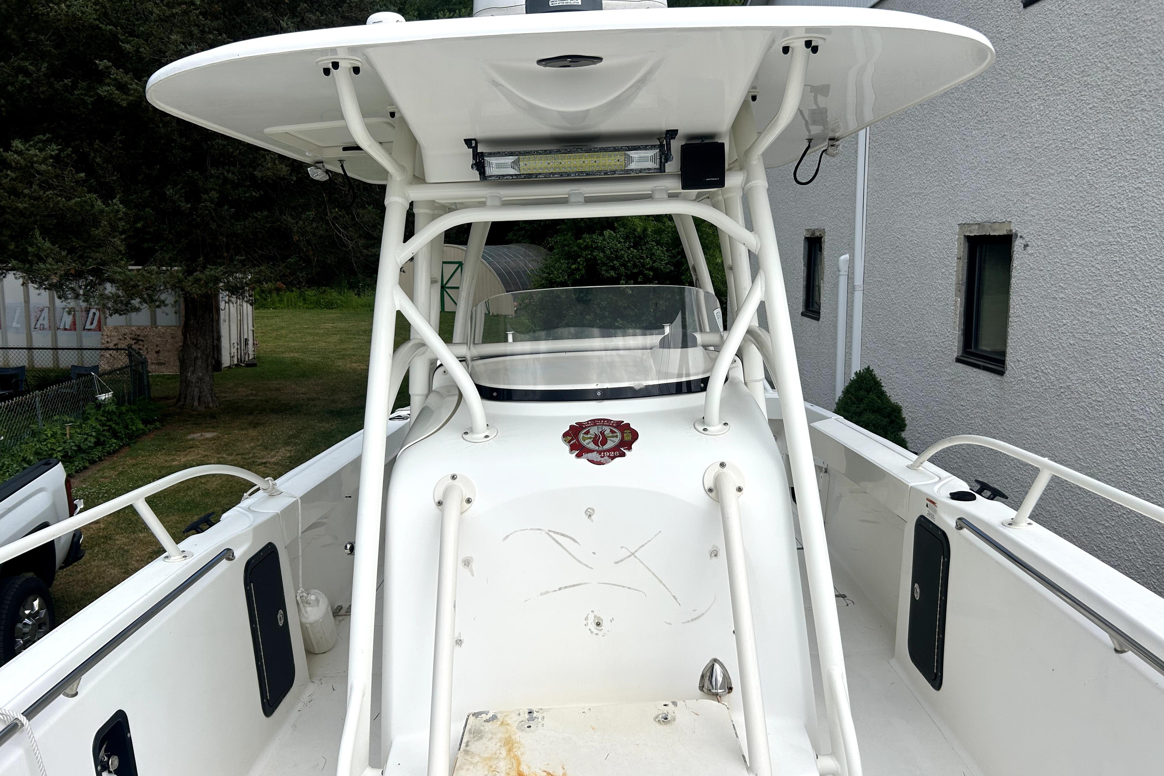 2012 Boston Whaler 320 Outrage boat with T-top and center console, docked outdoors.