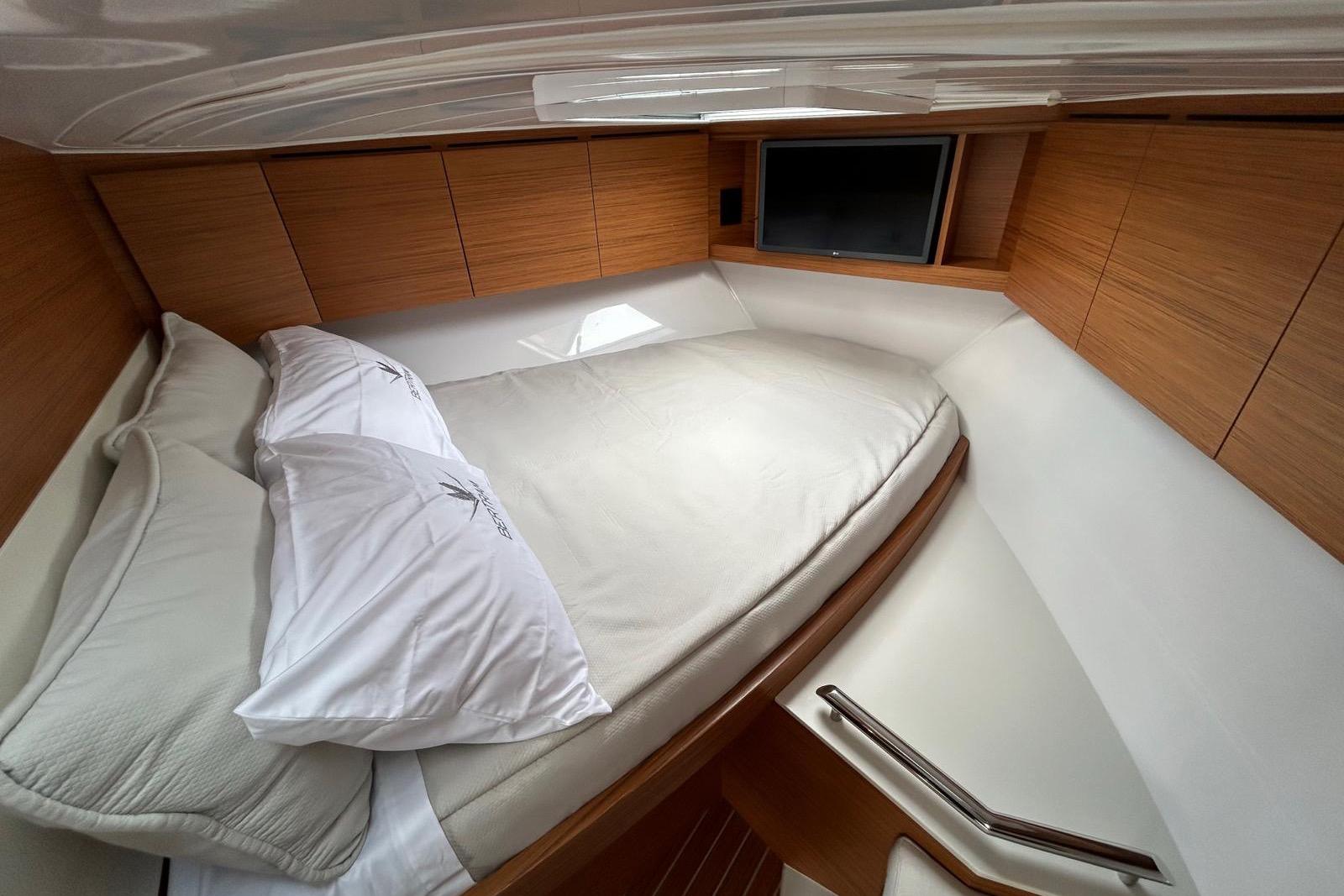 2023 Bertram Yacht 35 interior cabin with cozy bed and modern wood paneling.