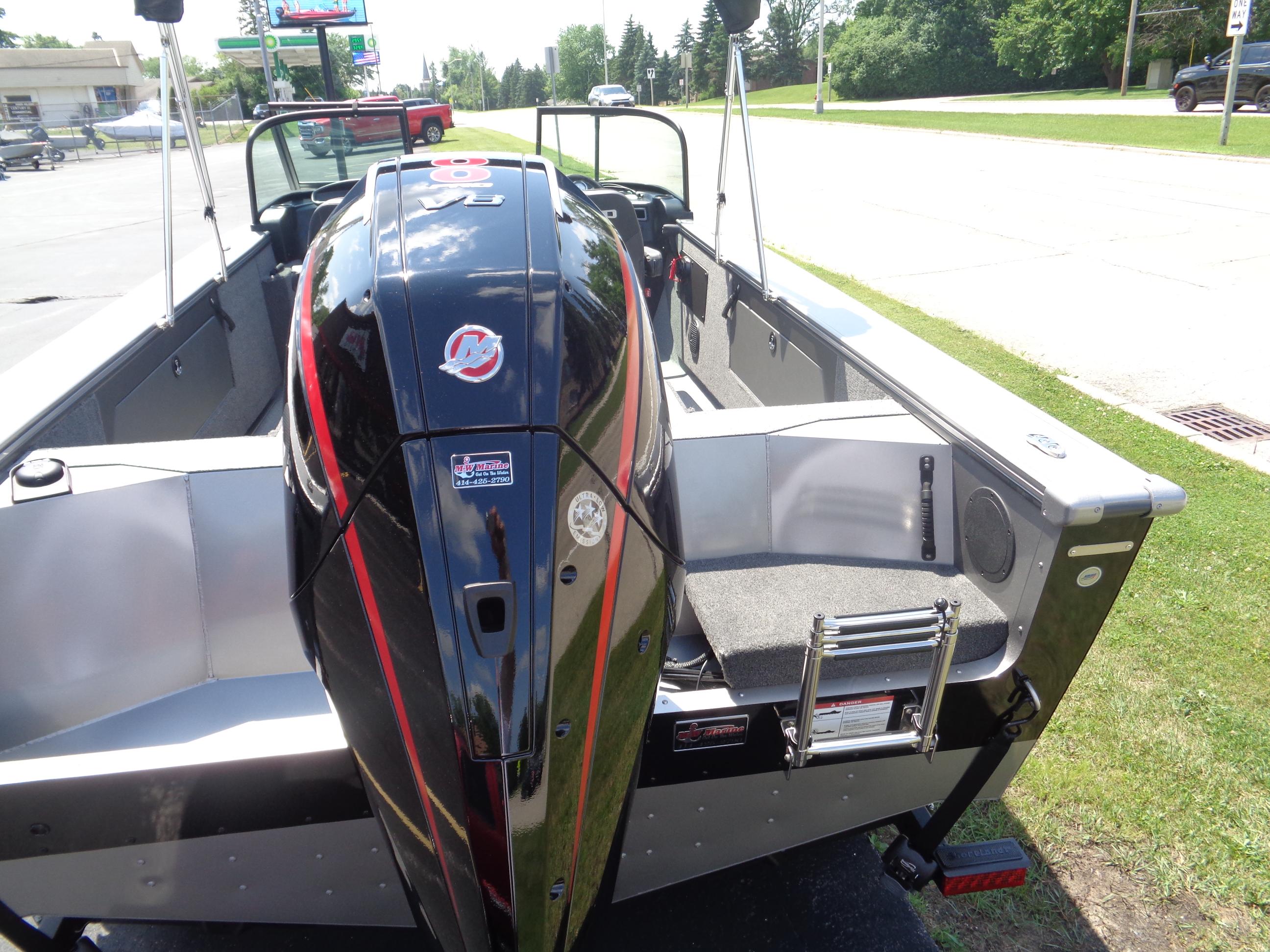 2025 Lund 2075 Fisherman boat with powerful outboard motor, parked on grass.