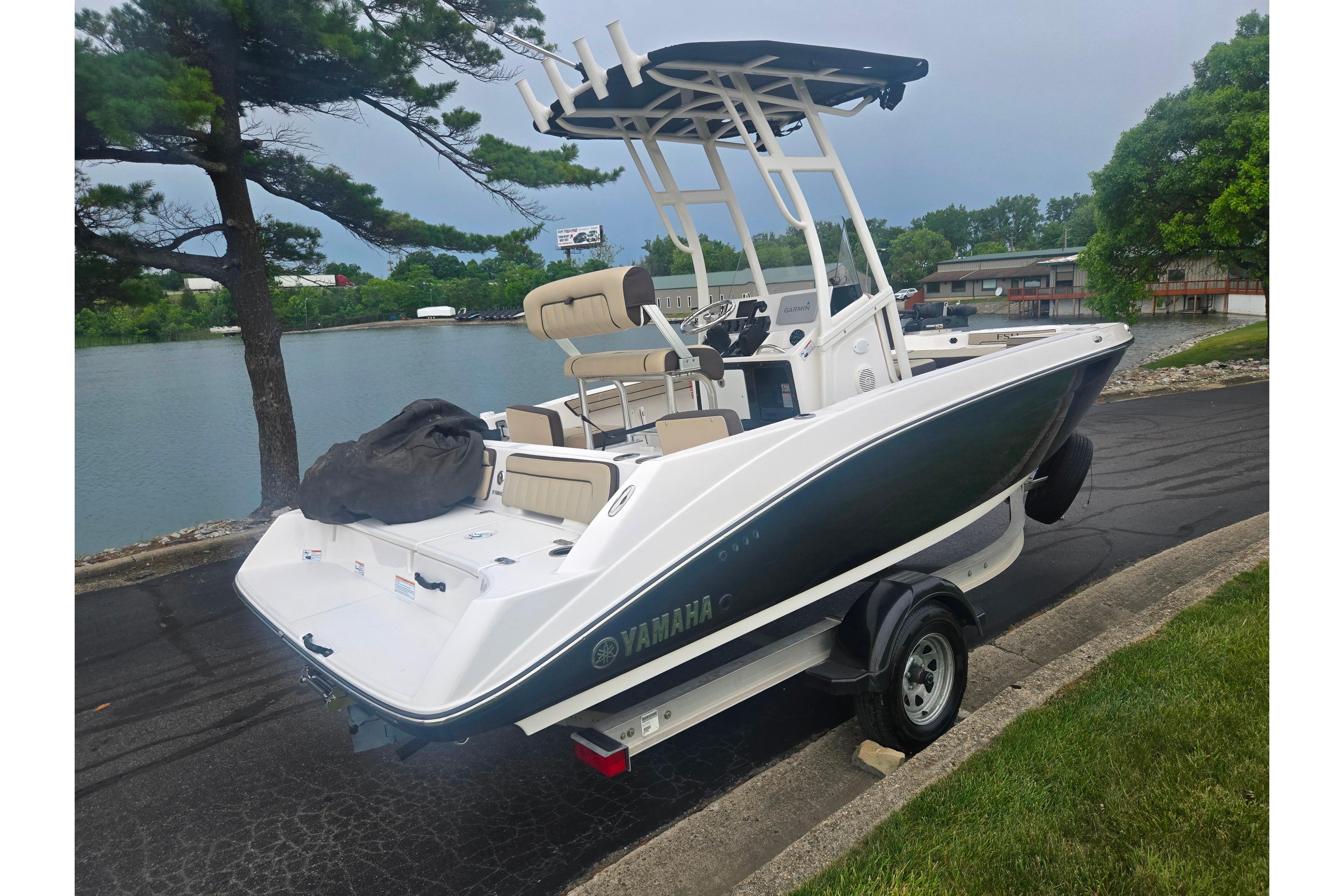 2022 Yamaha Boats 195 FSH Sport on trailer by a lakeside road.