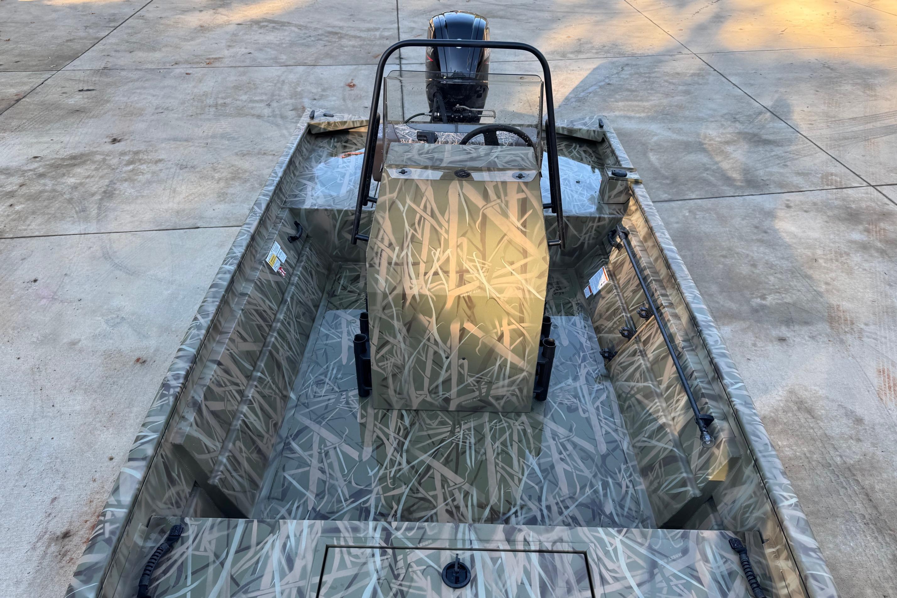 2026 Crestliner 1860 Retriever CC boat with camouflage design on concrete surface.
