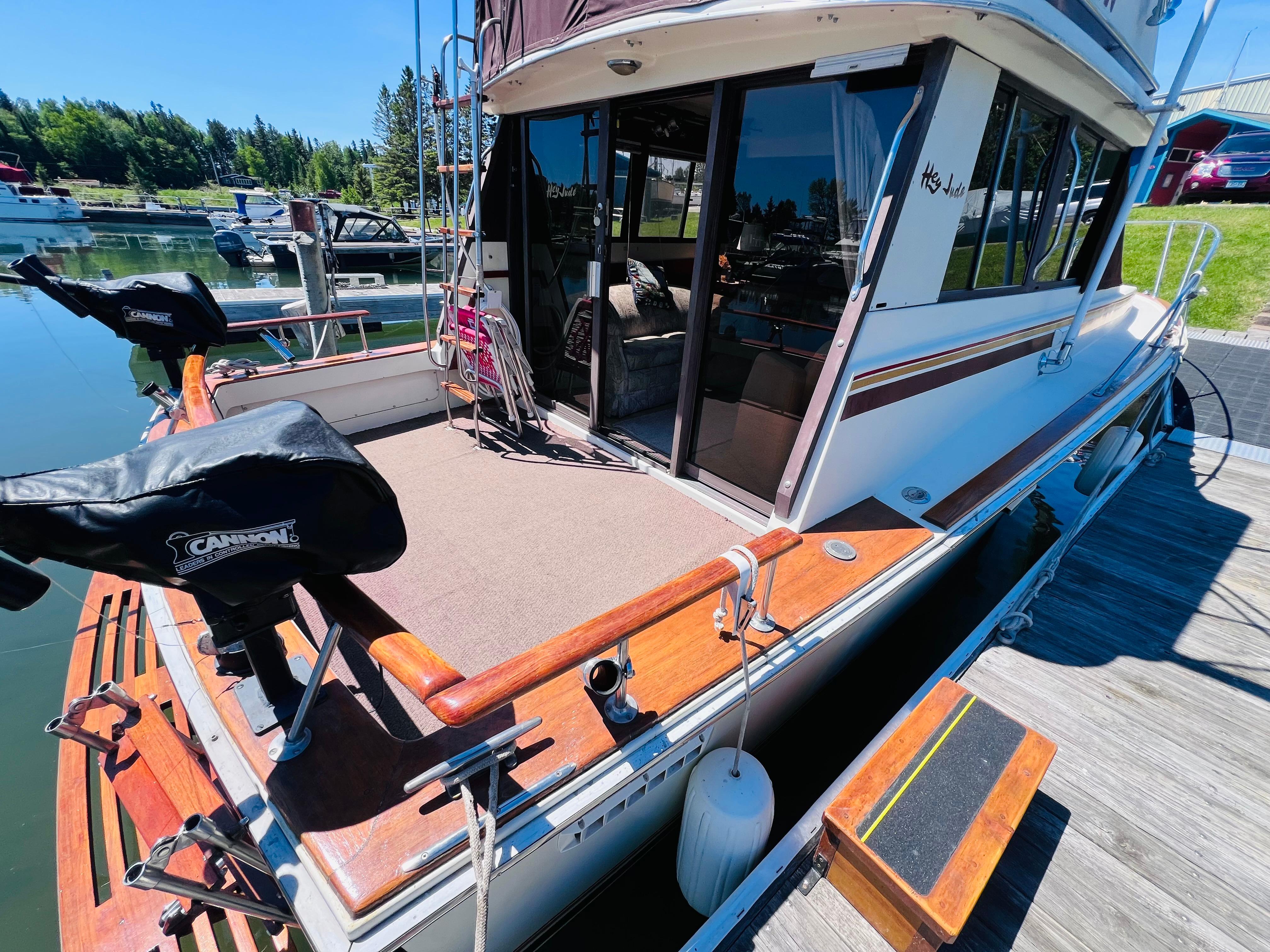 1982 Trojan F32 boat docked, featuring a spacious deck and covered equipment, in a serene marina setting.
