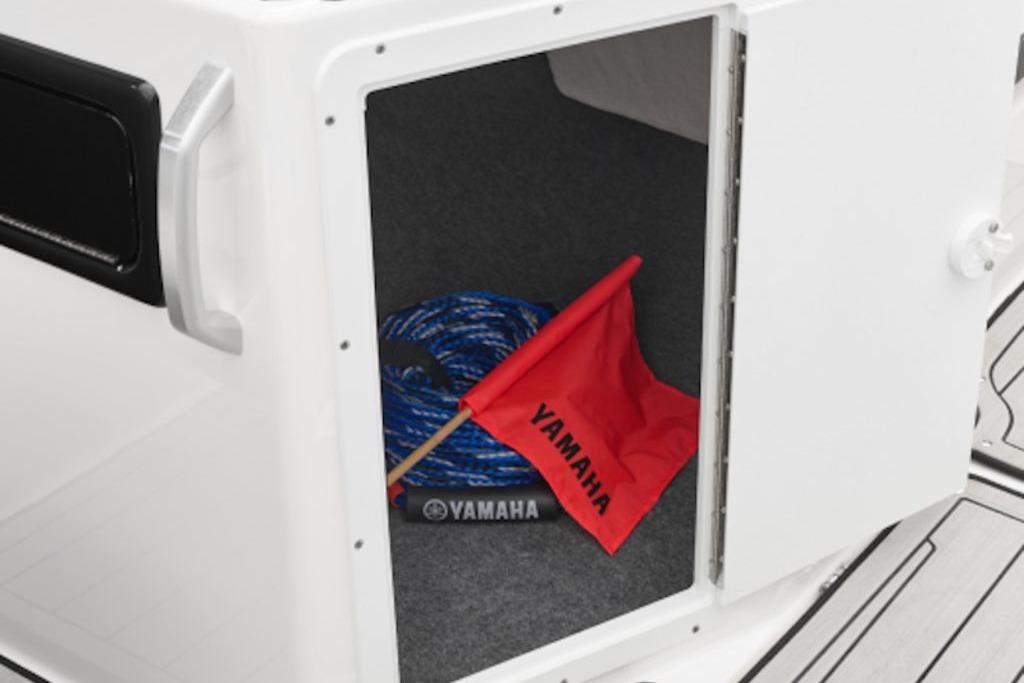 Open storage compartment on 2026 Yamaha Boats 195S with rope and red Yamaha flag.