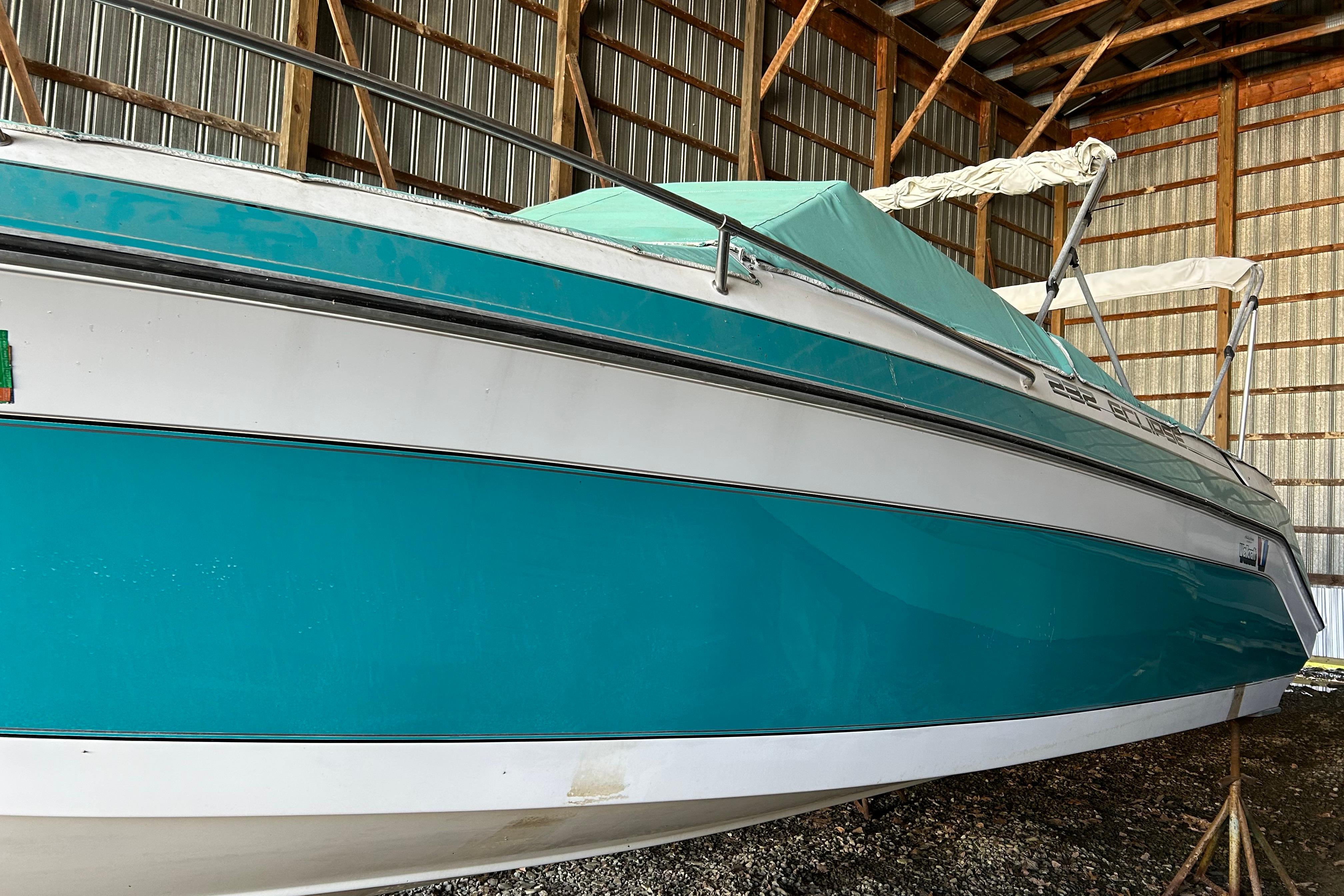 1991 Wellcraft 232 Eclipse boat in storage, teal and white exterior, covered and elevated.