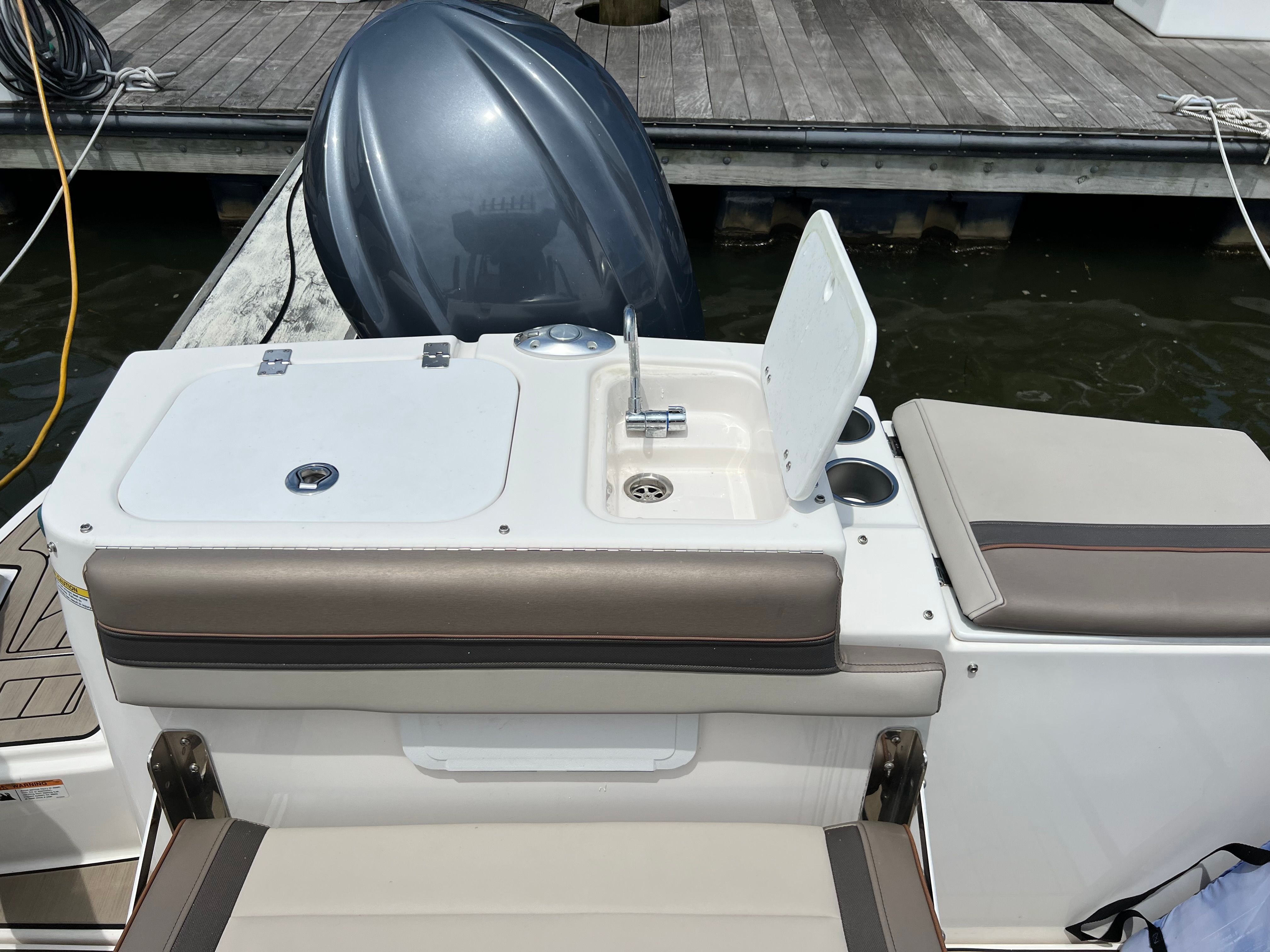 The image shows the stern of a Cutwater C-24 CW boat with a small sink and seating.