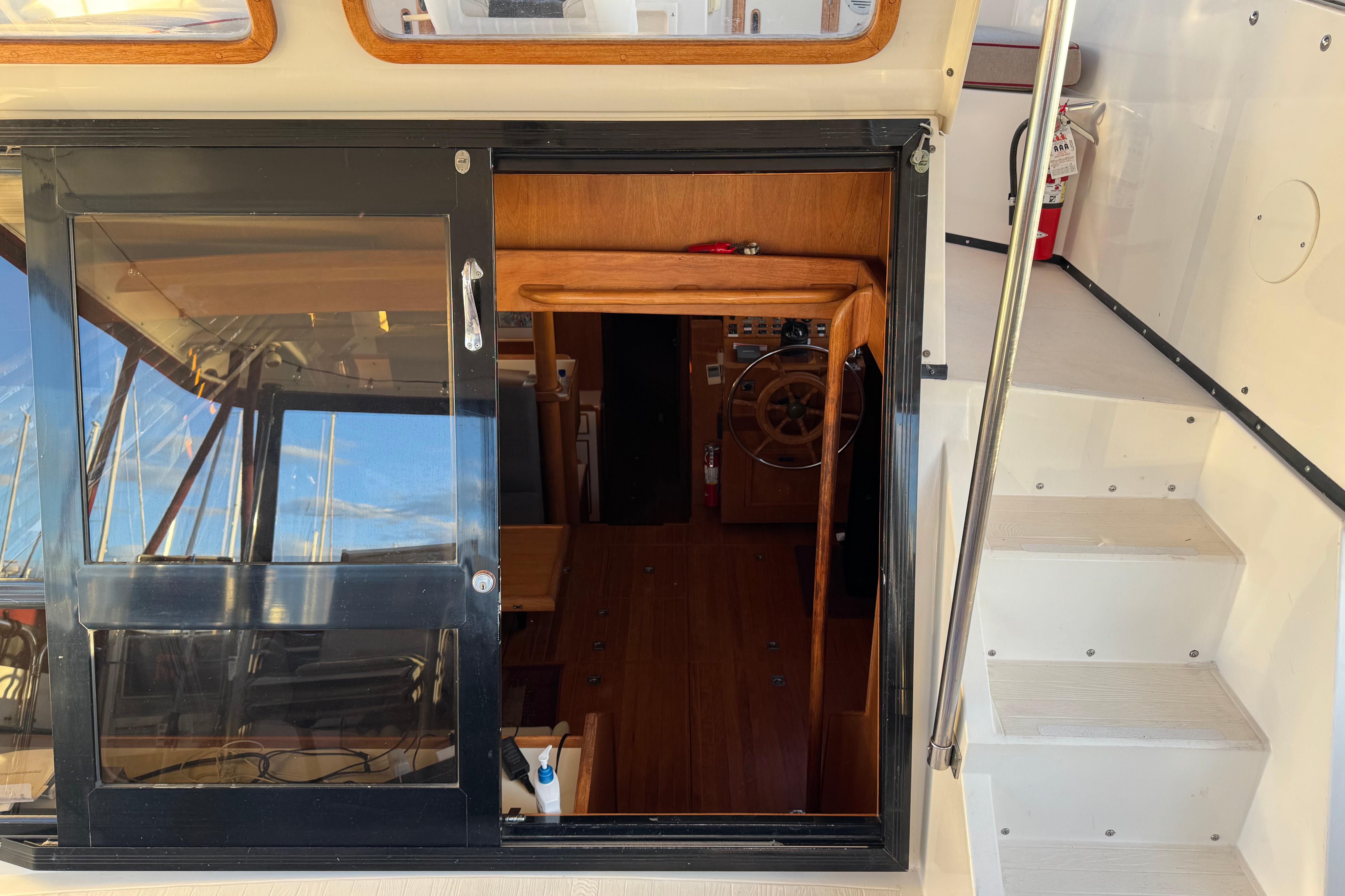 Interior view of a 1987 President 37 yacht, showcasing wooden helm and sliding door.