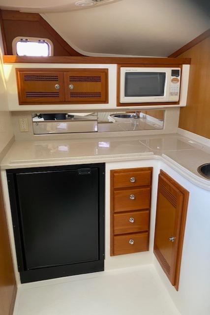 Compact kitchen area in a 2000 Cabo 35 Express boat with microwave and mini-fridge.
