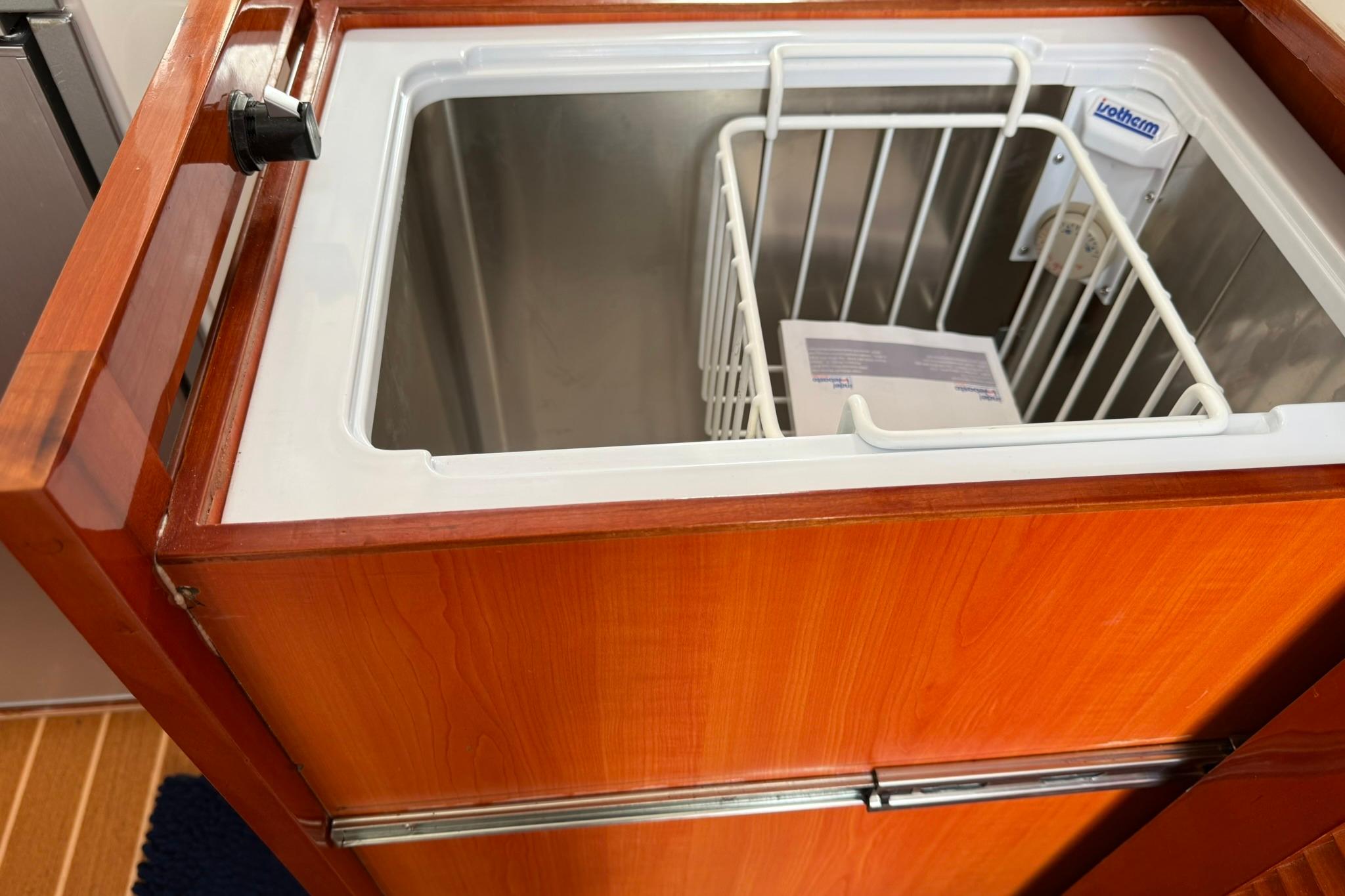 Built-in freezer on 2020 SeaPiper 35 boat with wooden finish and storage basket.