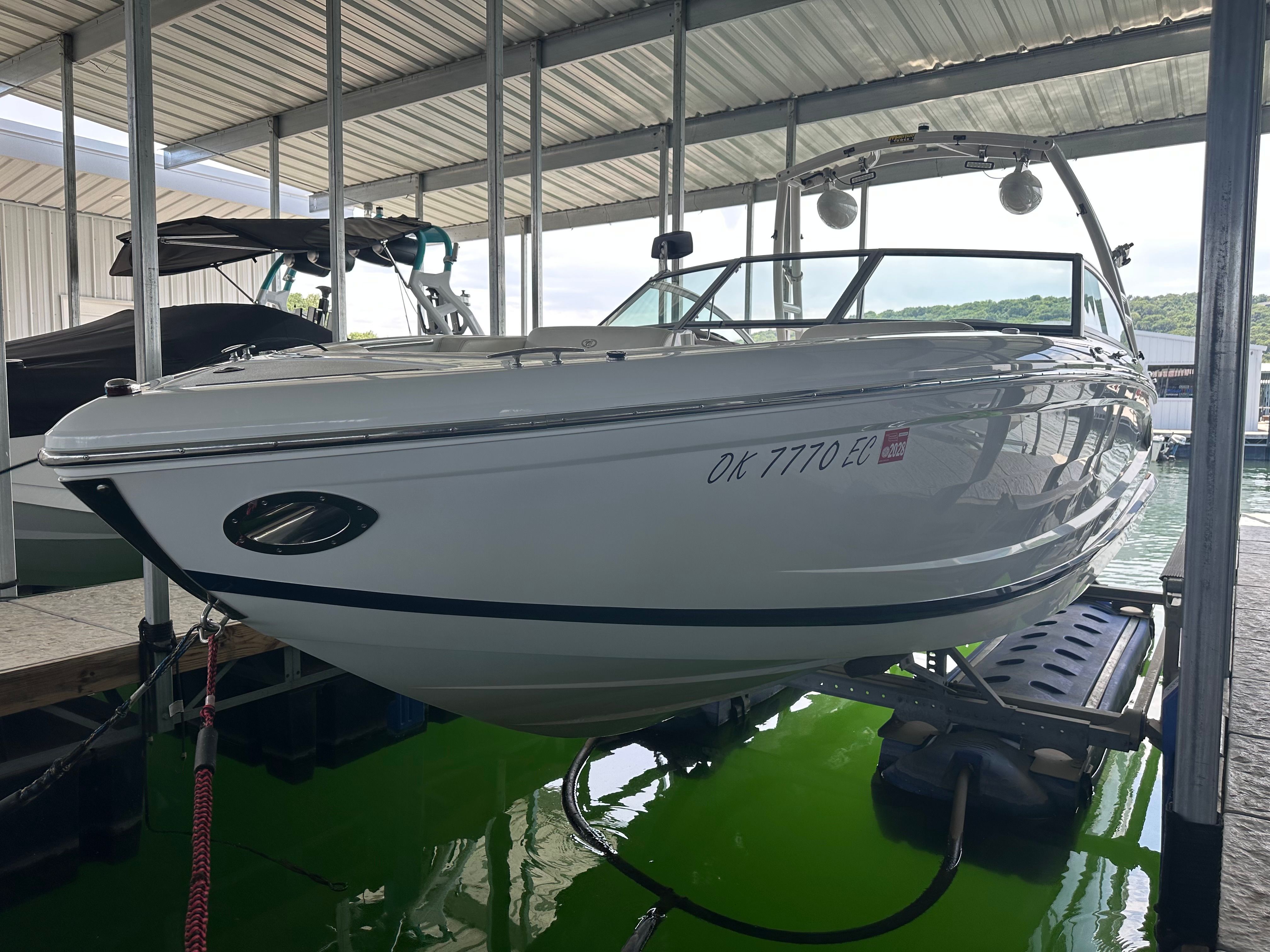 A white 2011 Cobalt A25 boat is in a covered dock on a lift system.