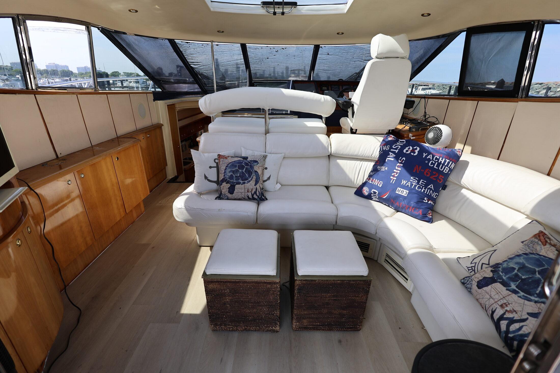 Luxurious interior of 1999 Neptunus 54 Express yacht with white leather seating and nautical decor.