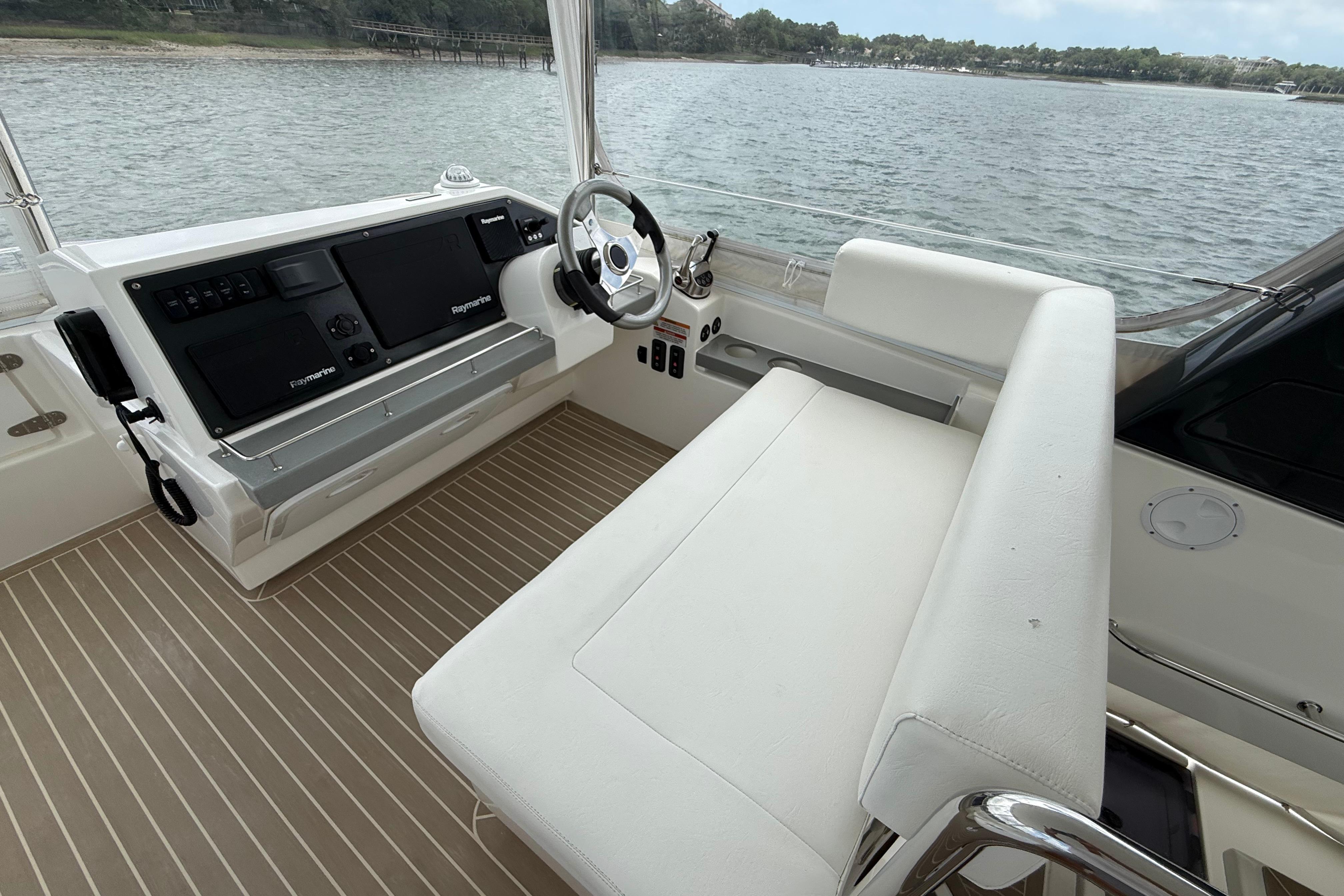 Helm of 2021 Leopard 43 Powercat with dual screens and white seating, overlooking water.