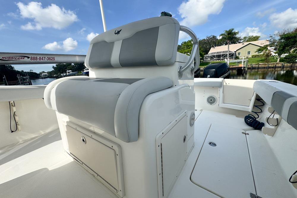 2018 Mako 284 Center Console boat interior with seating and storage, docked by a scenic waterfront.