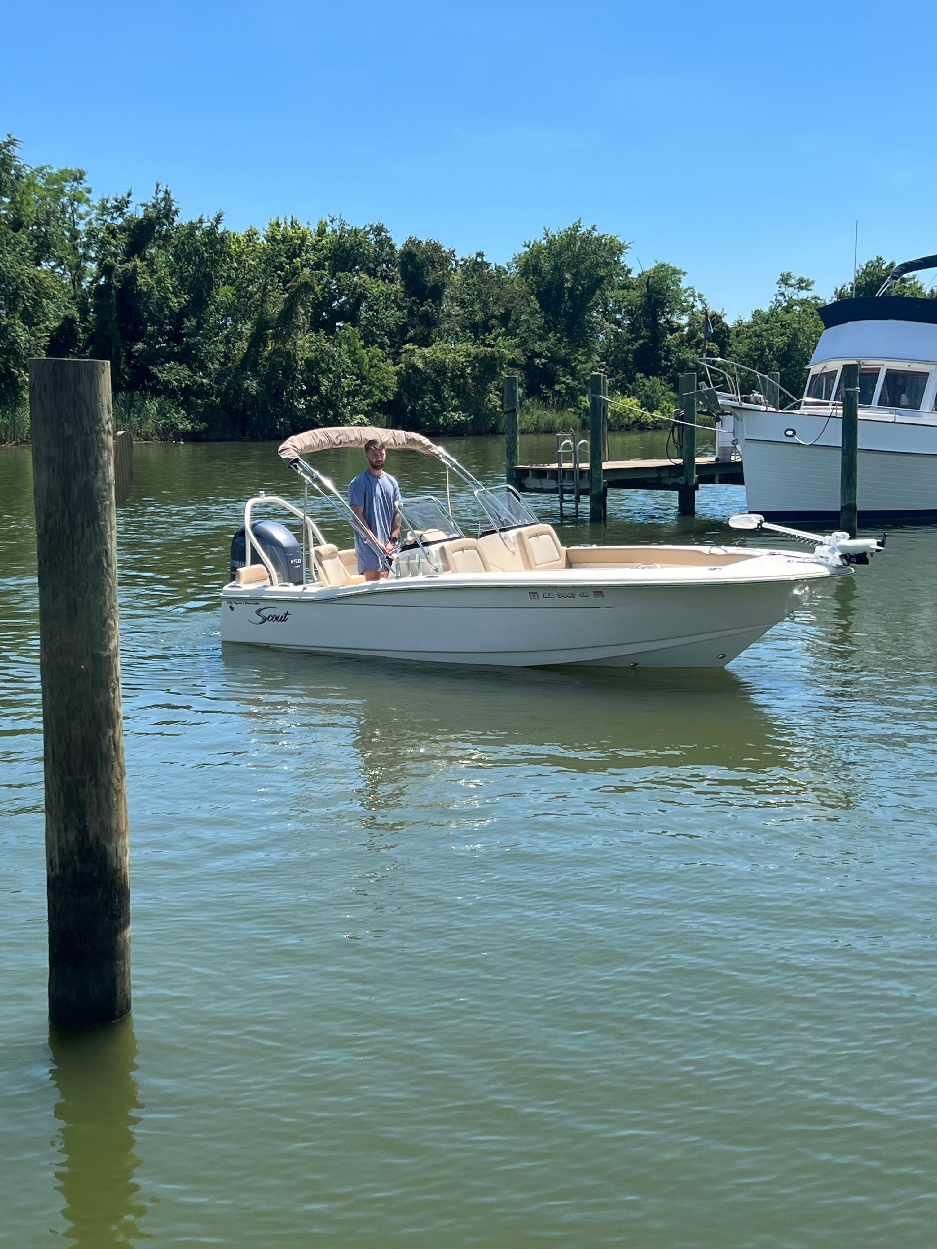 A 2021 Scout 195 Sport Dorado boat on calm water with a person on board.