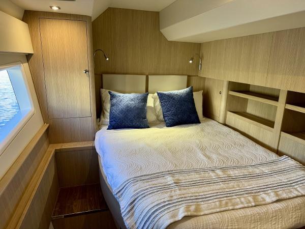 Luxurious bedroom interior of 2022 Aquila 44 yacht with modern wood finish and cozy bedding.
