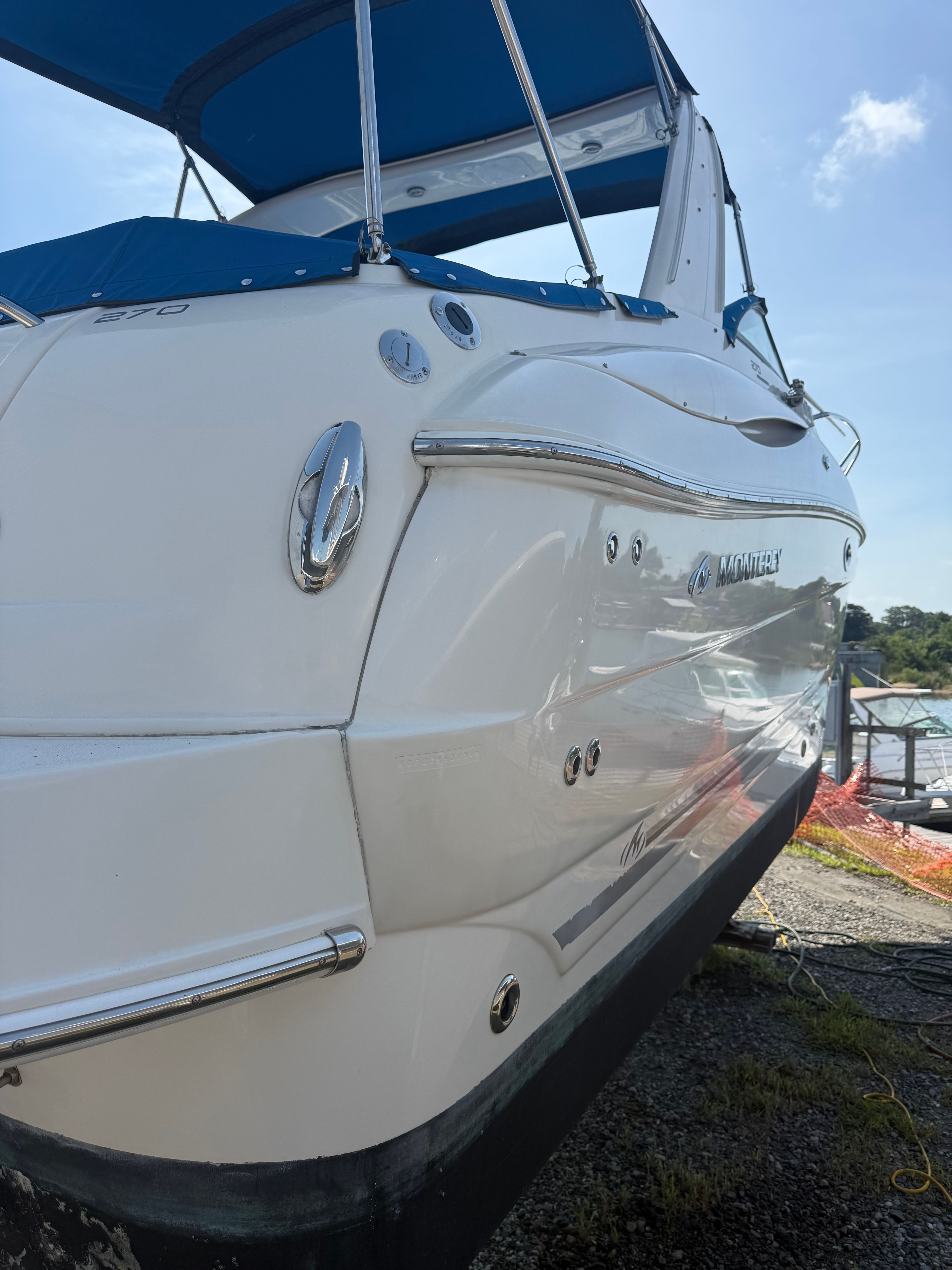 A 2006 Monterey 270 Cruiser with a blue canopy, on a dry dock.