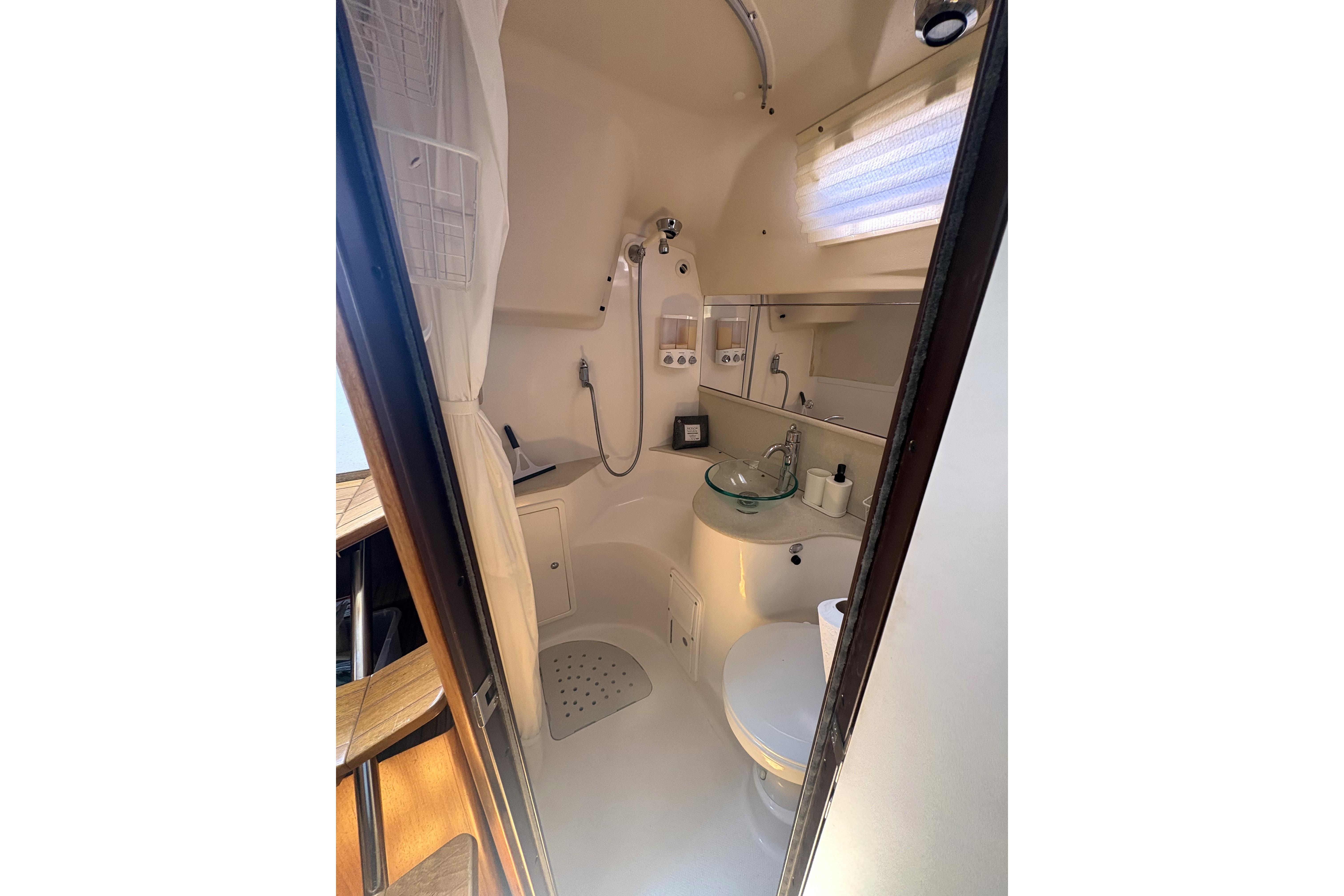Compact bathroom in a 2011 Catalina 355 sailboat, featuring a shower, sink, and toilet.