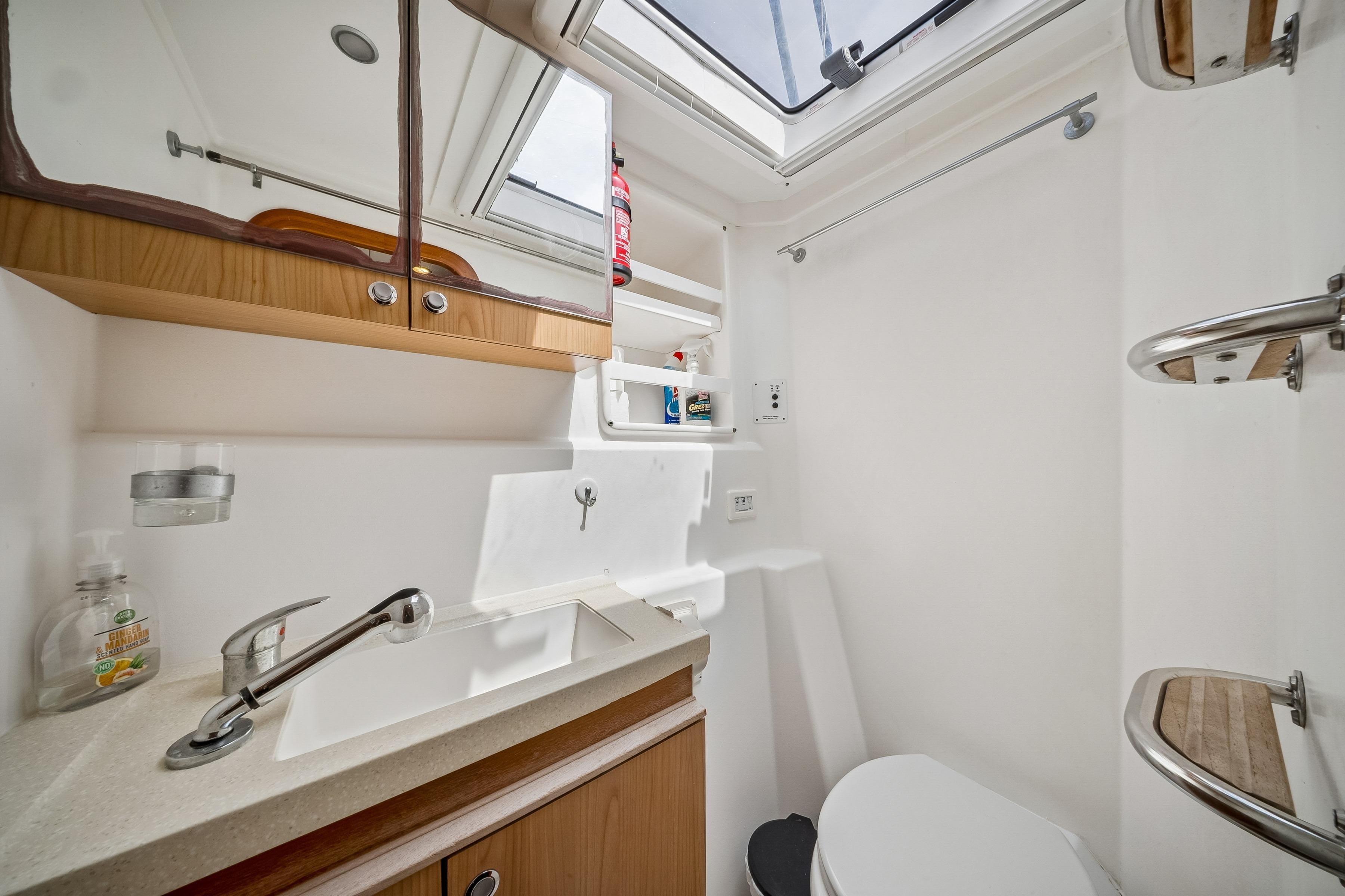 Compact bathroom in 2009 Catana 65 yacht with sink, toilet, and storage.