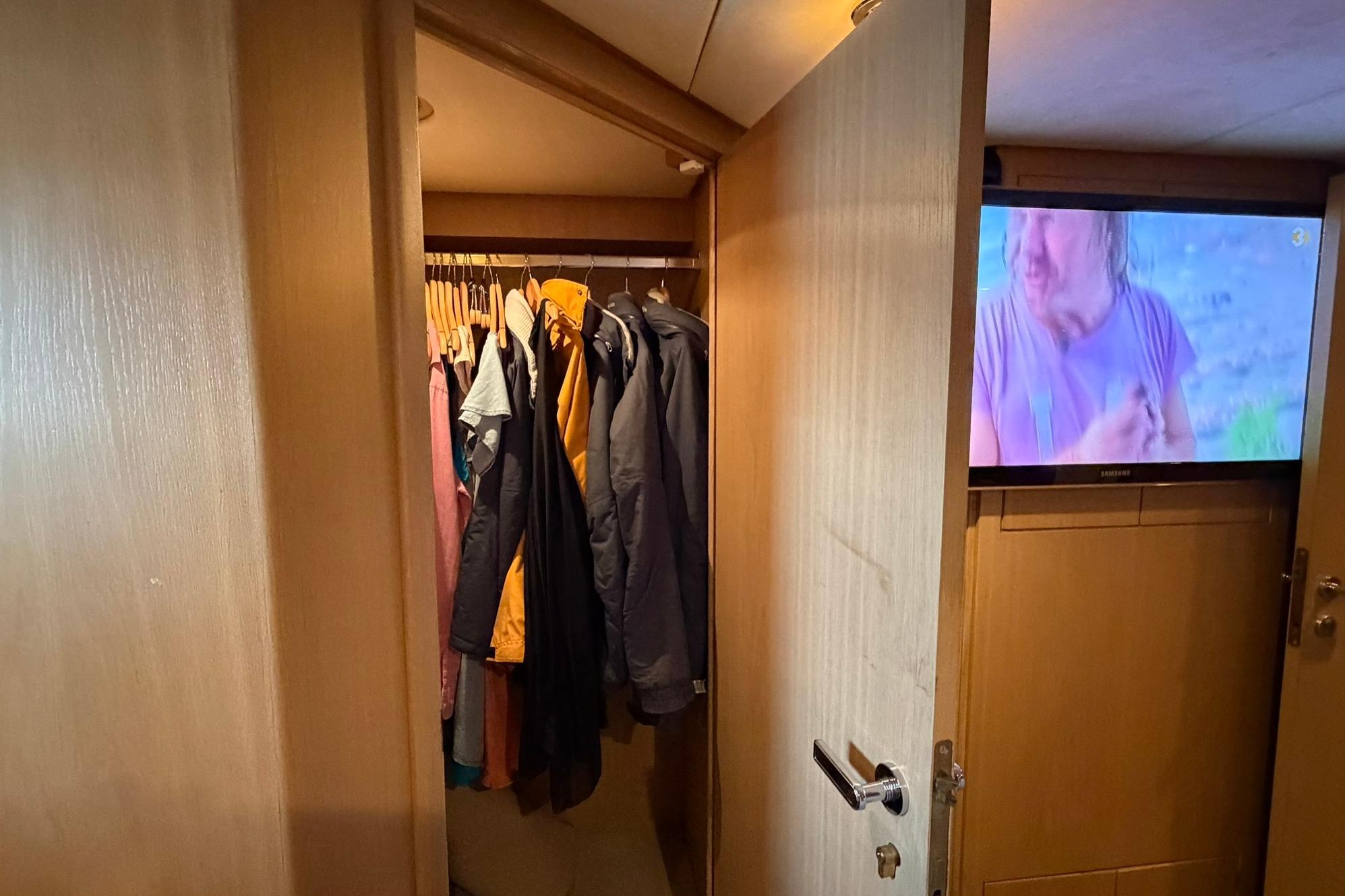 Closet with hanging clothes and TV in Lowland Netship 97 yacht interior.