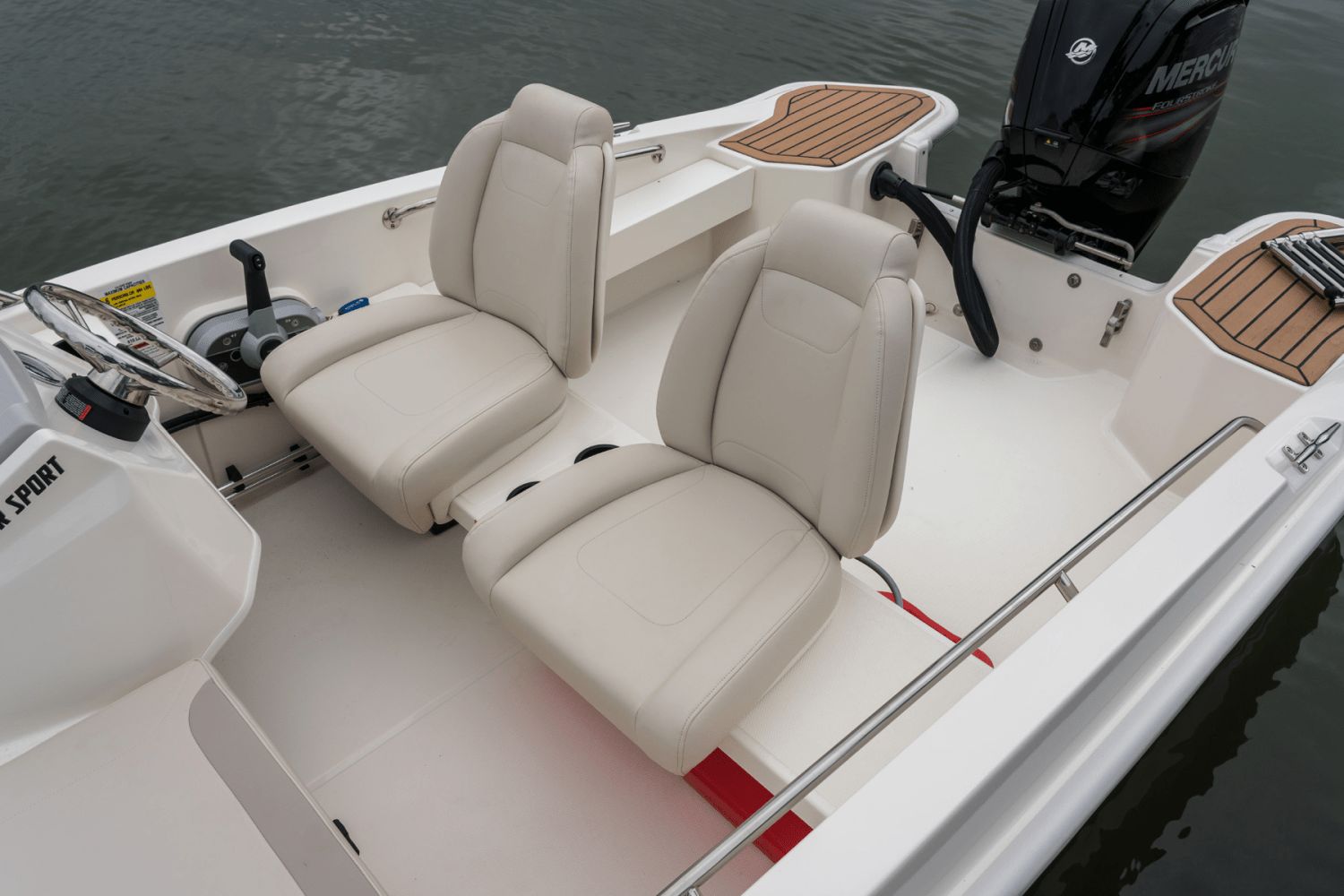 Interior of a Boston Whaler 160 Super Sport with two beige seats and a Mercury engine.