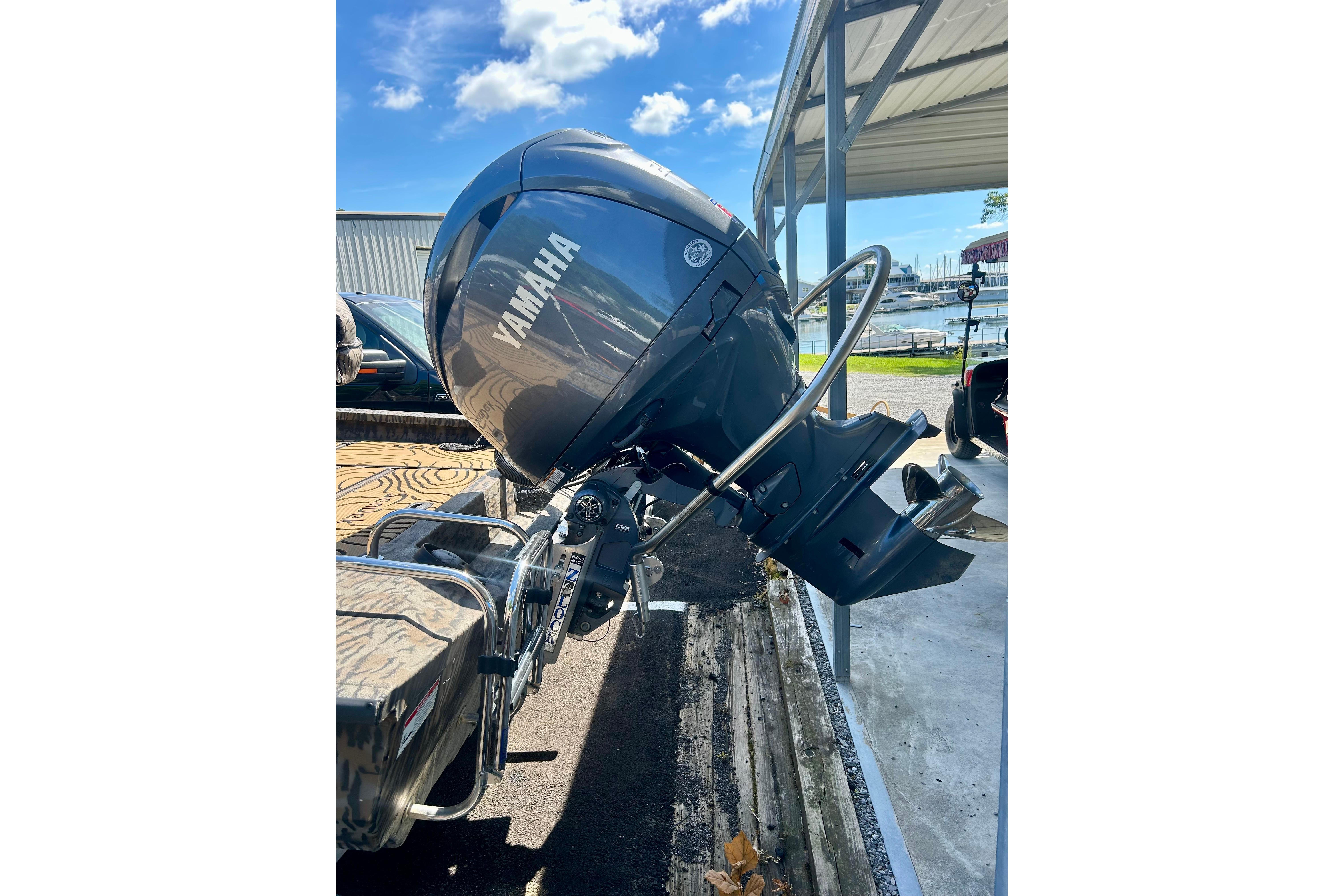 2025 Xpress H22B Bay boat with Yamaha outboard motor, parked under a metal canopy.